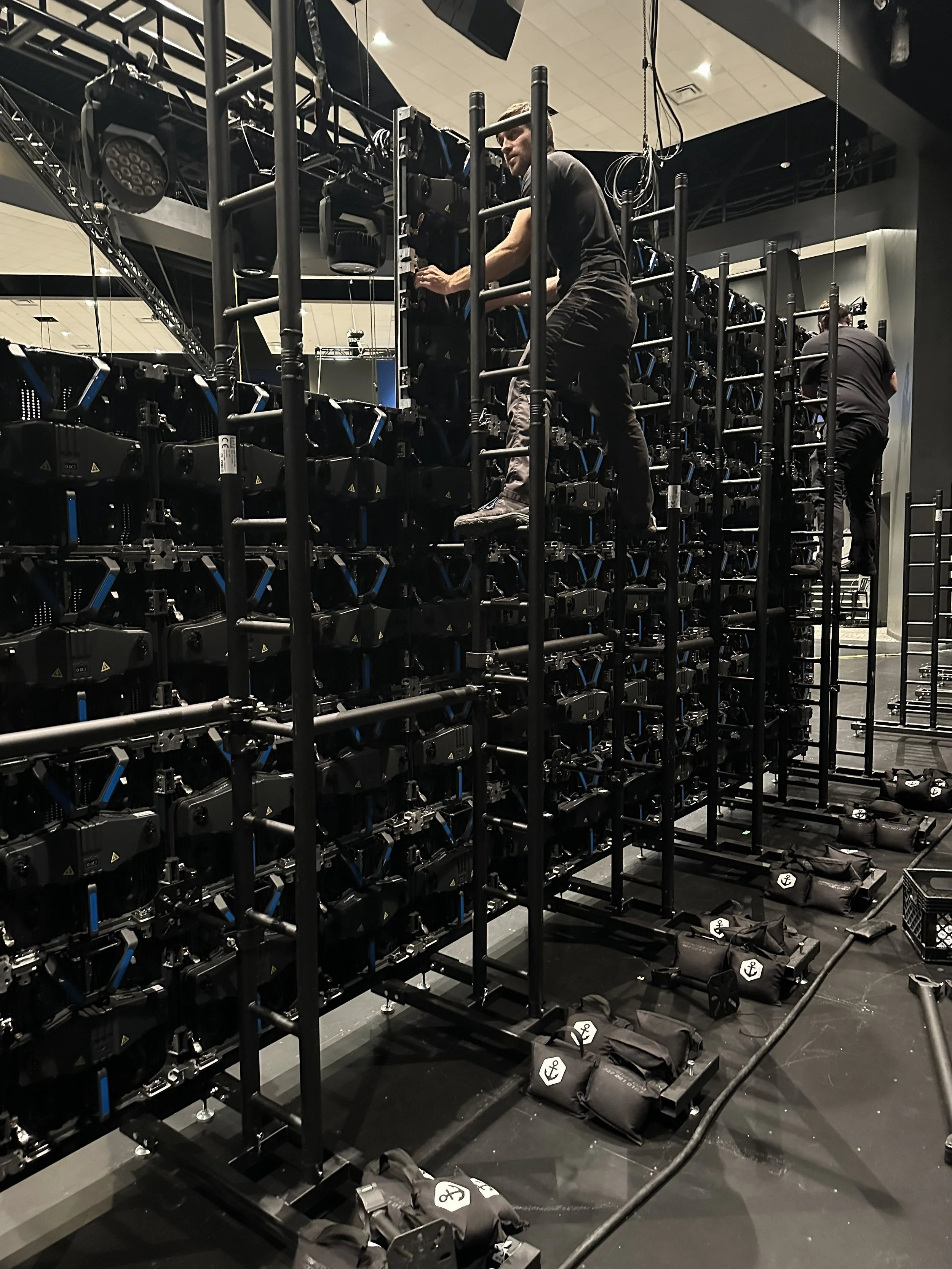 Workers setting up large LED panels on a stage.