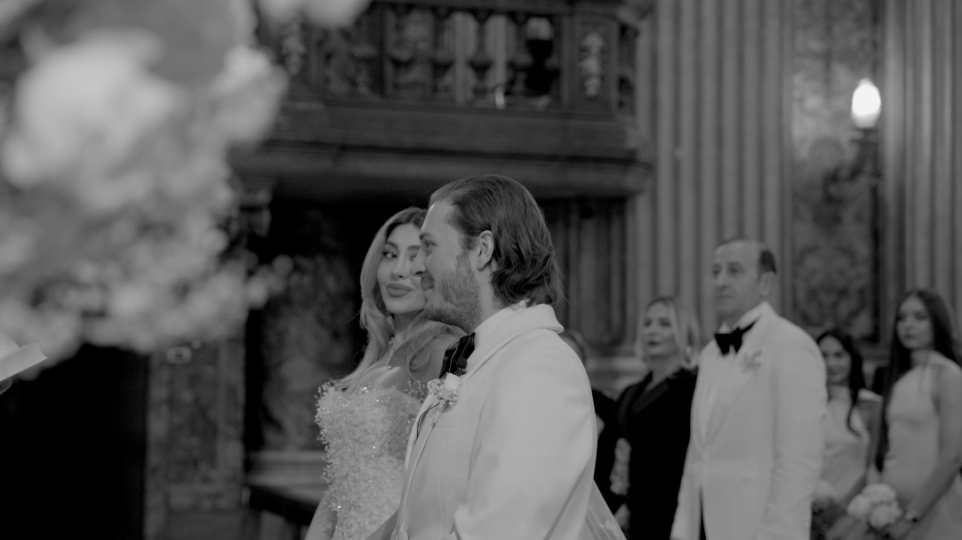 Bride and groom standing at the altar during their wedding ceremony in a church, with guests in the background.