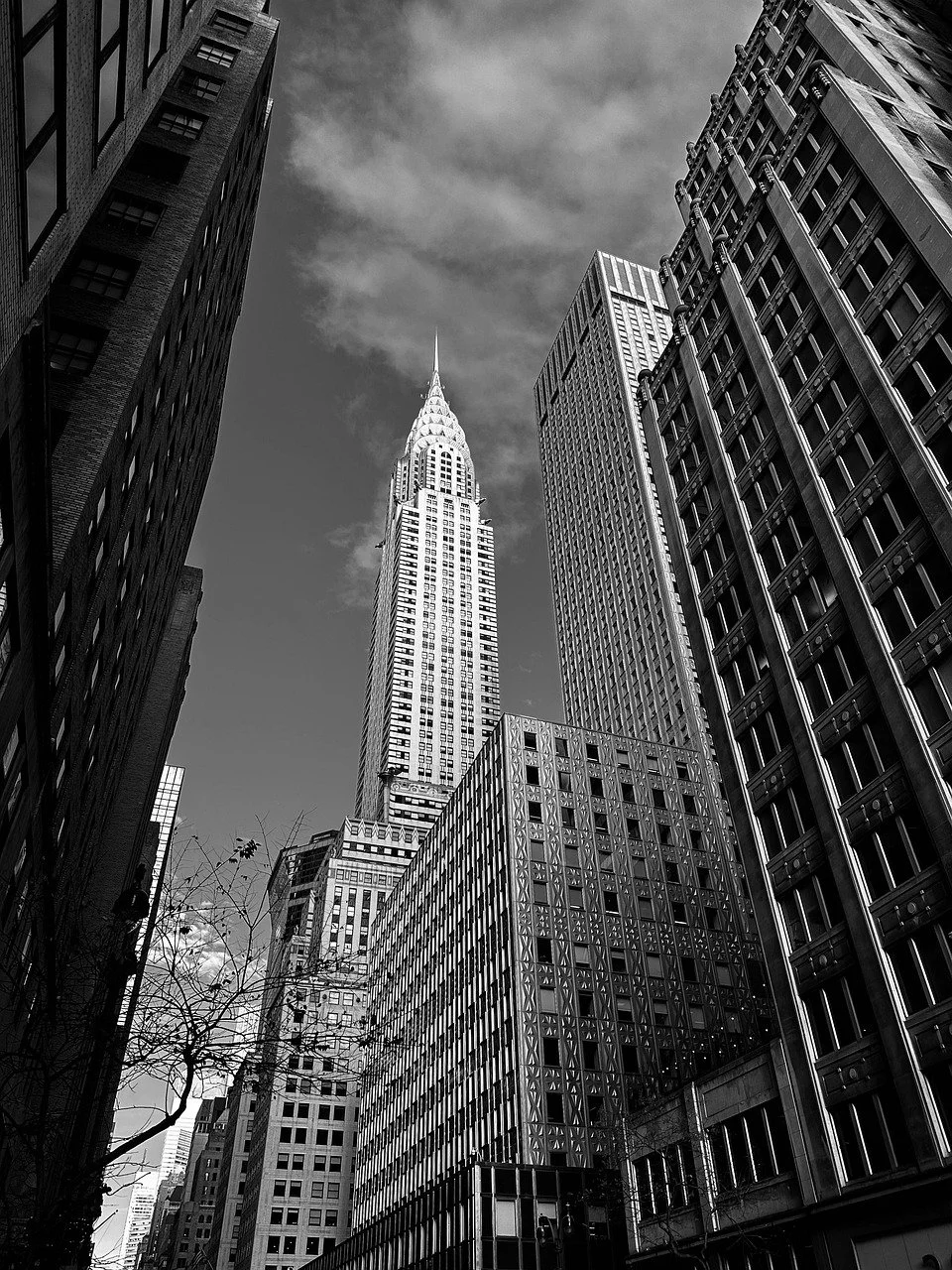 Black and white photo of tall skyscrapers in a city, featuring the Chrysler Building with its spire in the center.