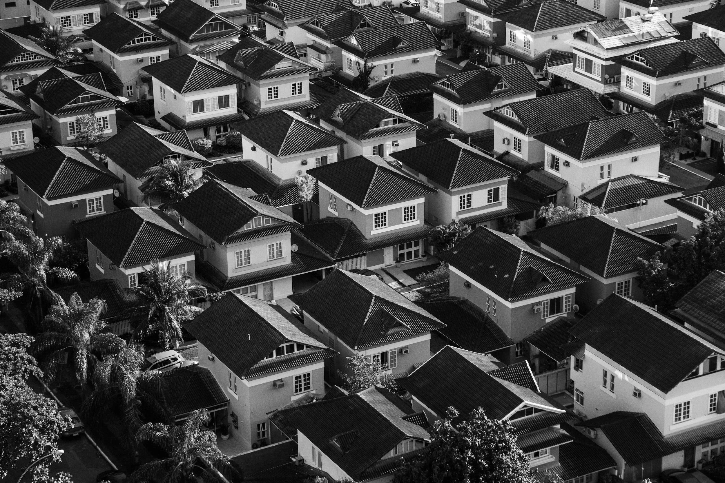 Aerial view of a neighborhood with closely packed houses with tiled roofs in black and white.