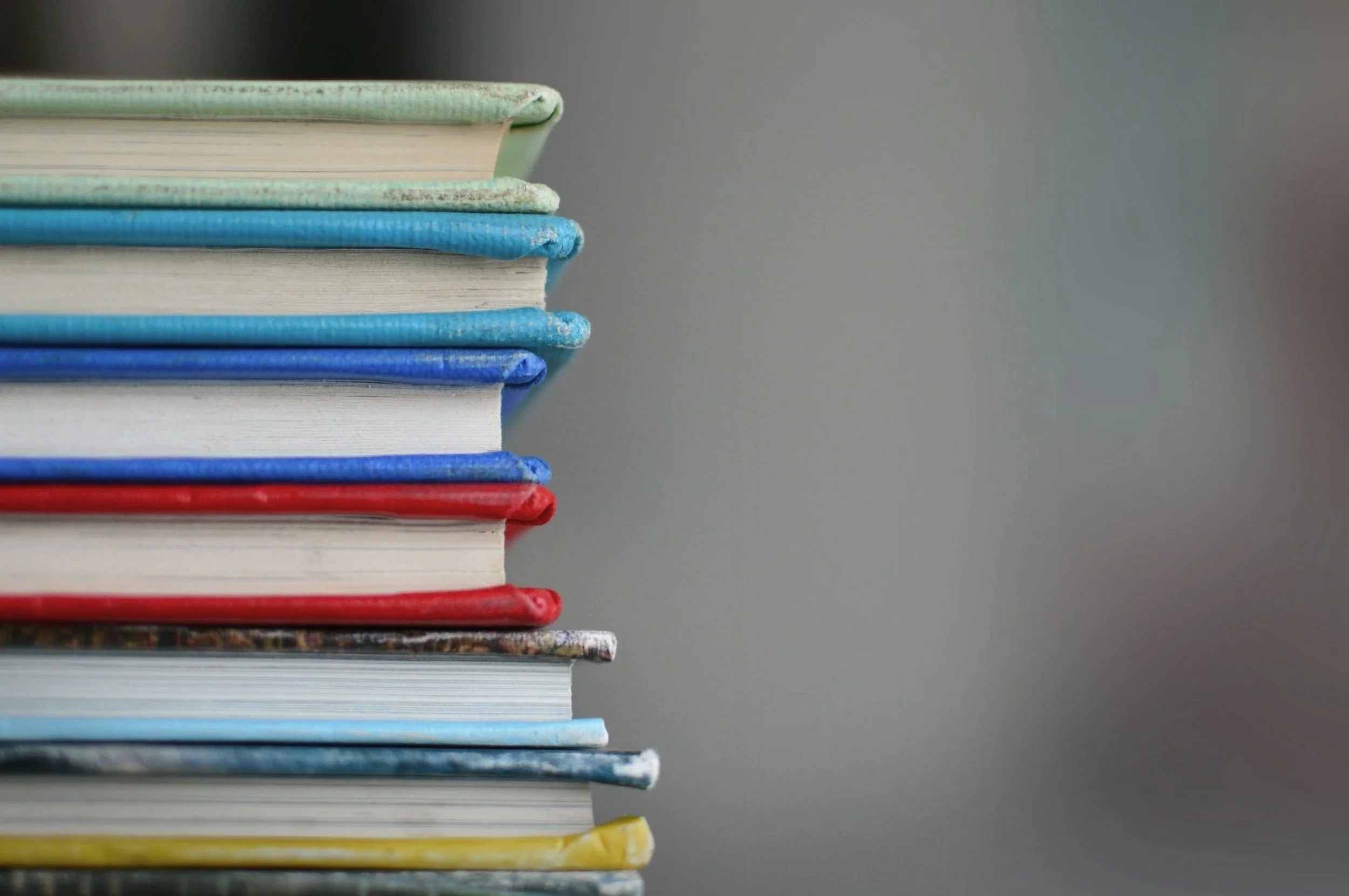 Stack of colorful books on a gray background.