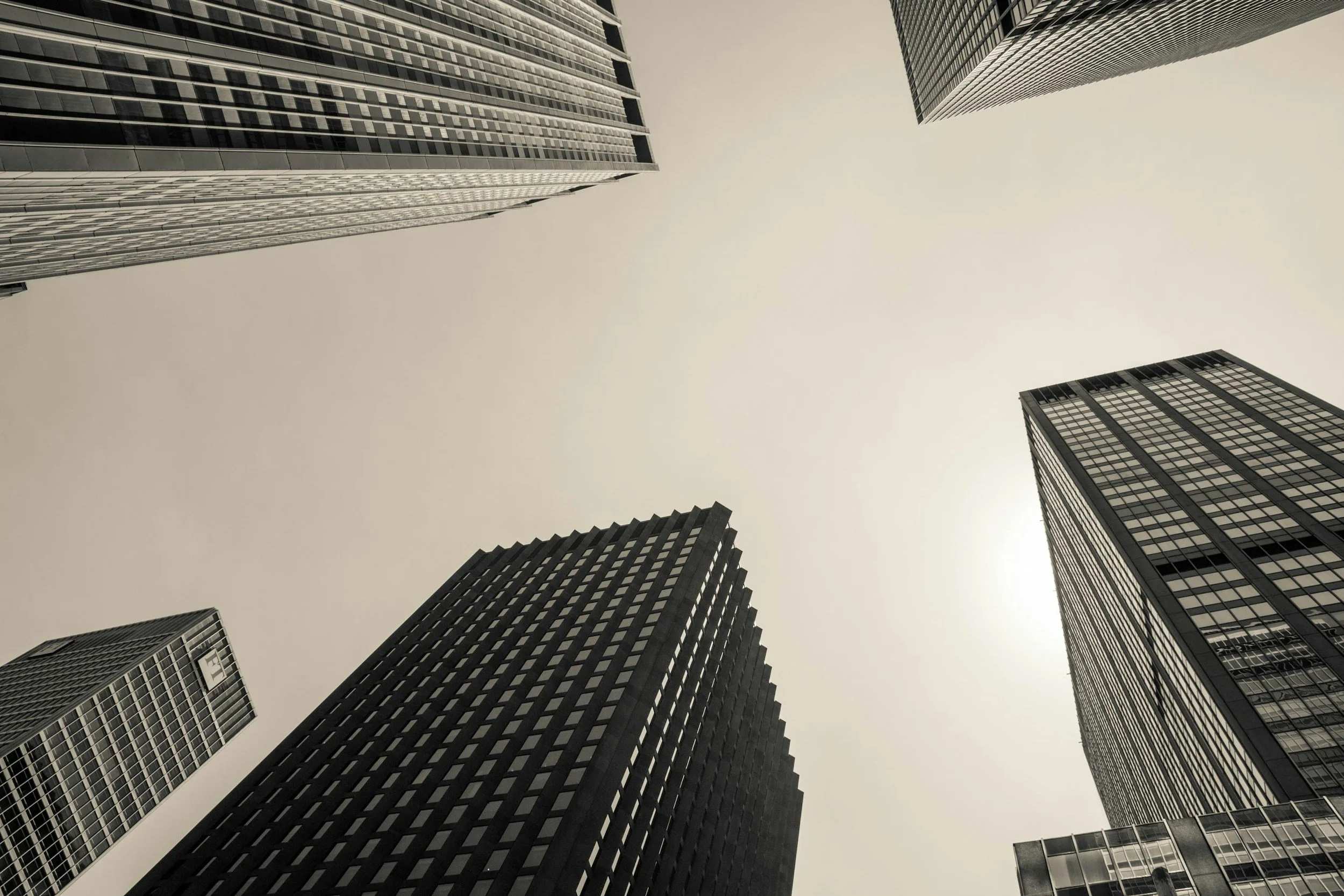 Several tall modern skyscrapers viewed from below against a pale sky.