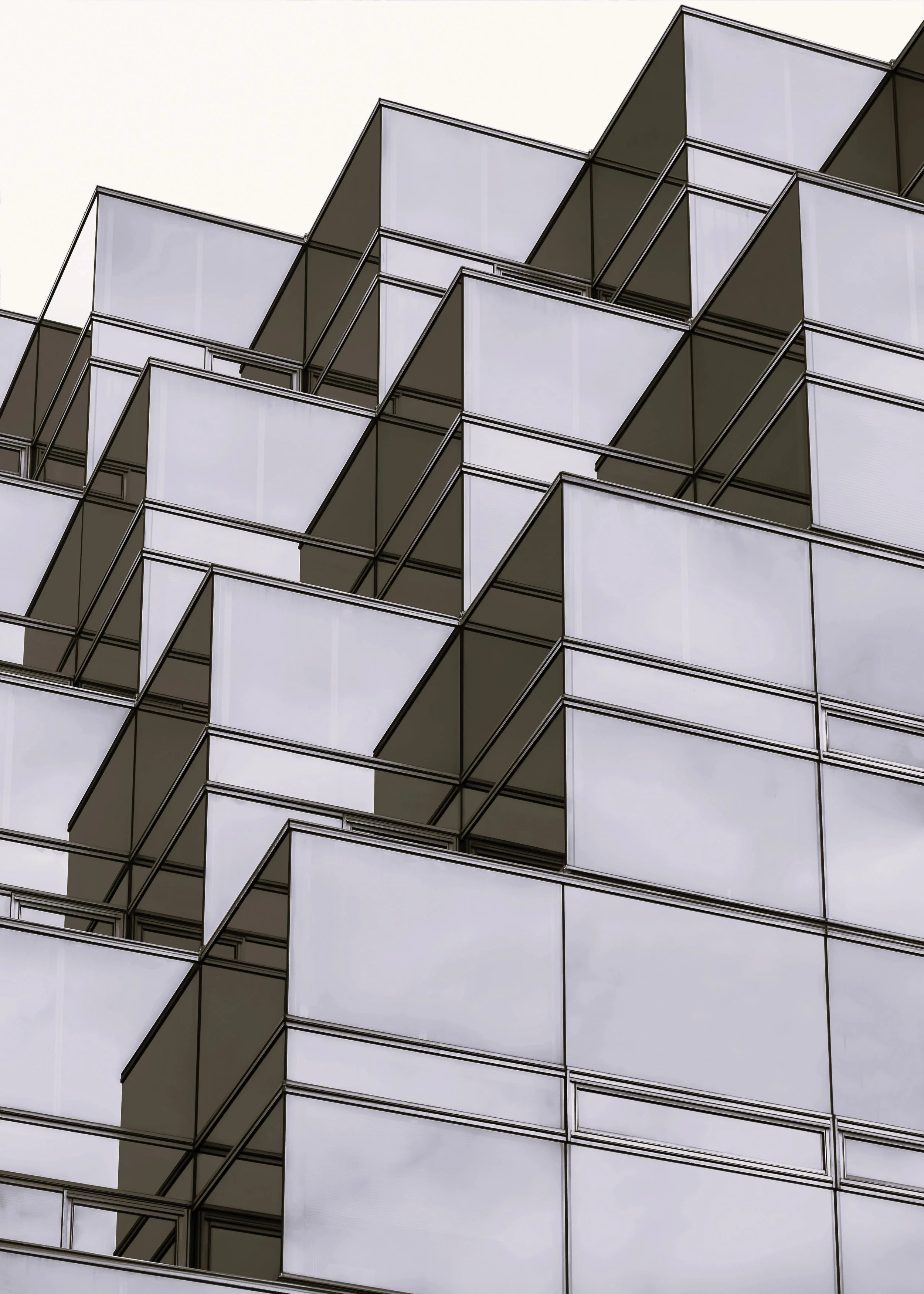 Close-up of modern geometric building with multiple glass balconies and reflections.