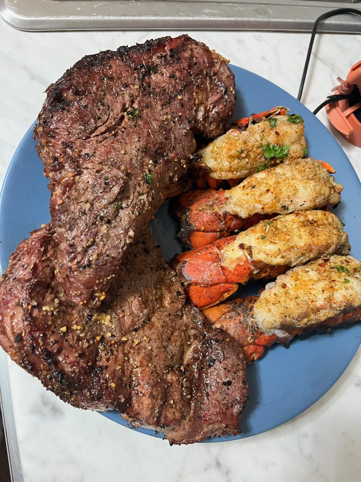 Surf and turf with grilled steak and seasoned lobster tails, part of a luxury in-home dining experience