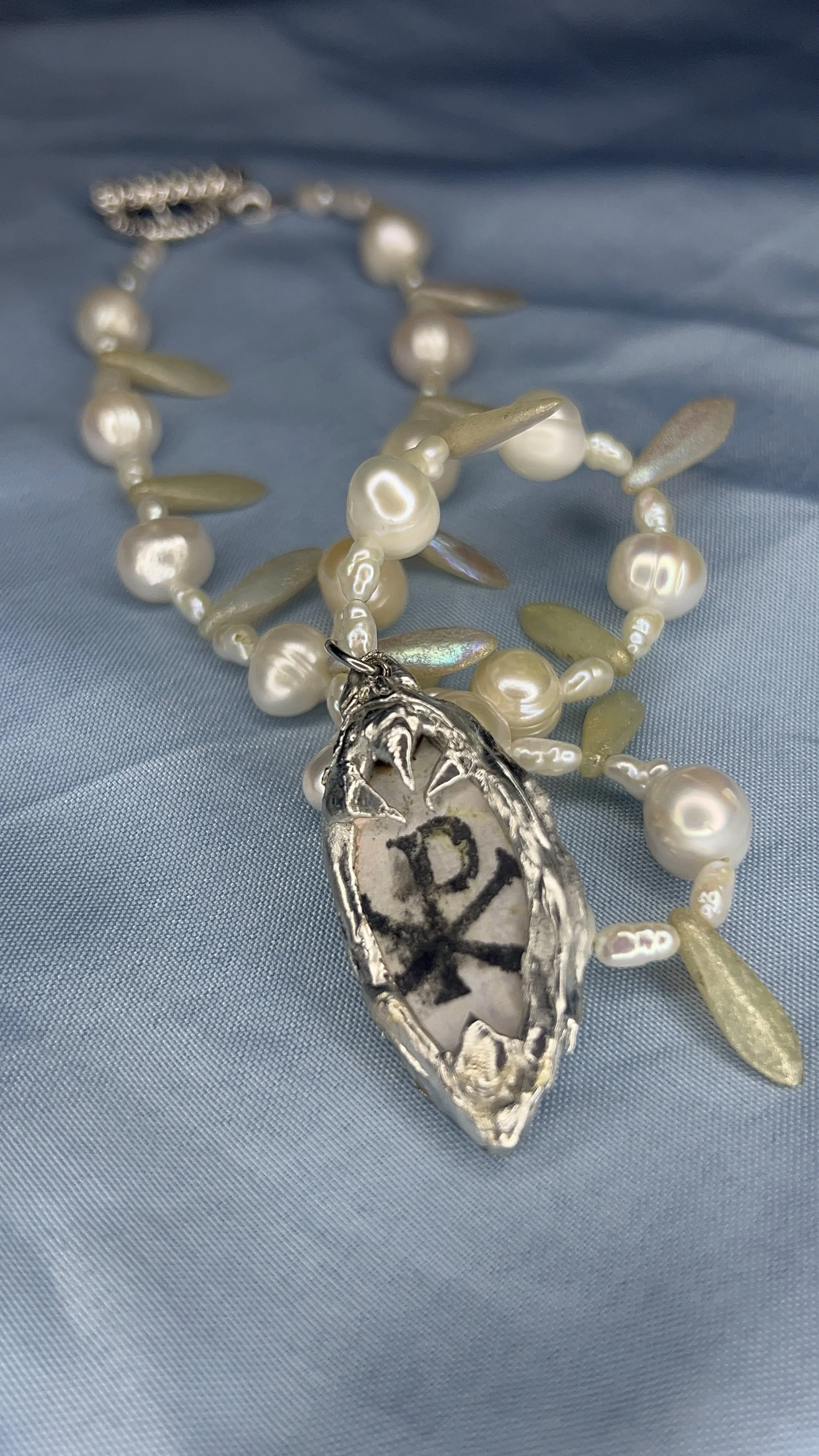 Pearl and gold bead necklace with a soldered pendant containing a Chi Rho symbol on its back.