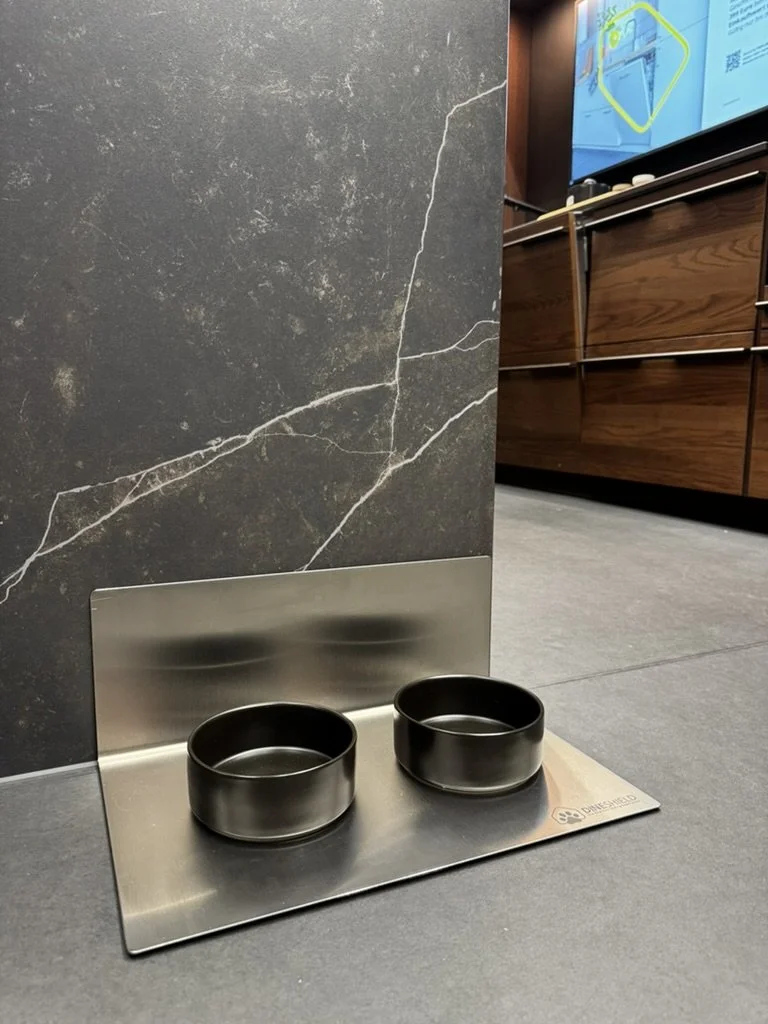 DineShield Edelstahl-Napfunterlage mit zwei schwarzen Näpfen vor dunkler Marmorwand – modernes Design in edler Küche