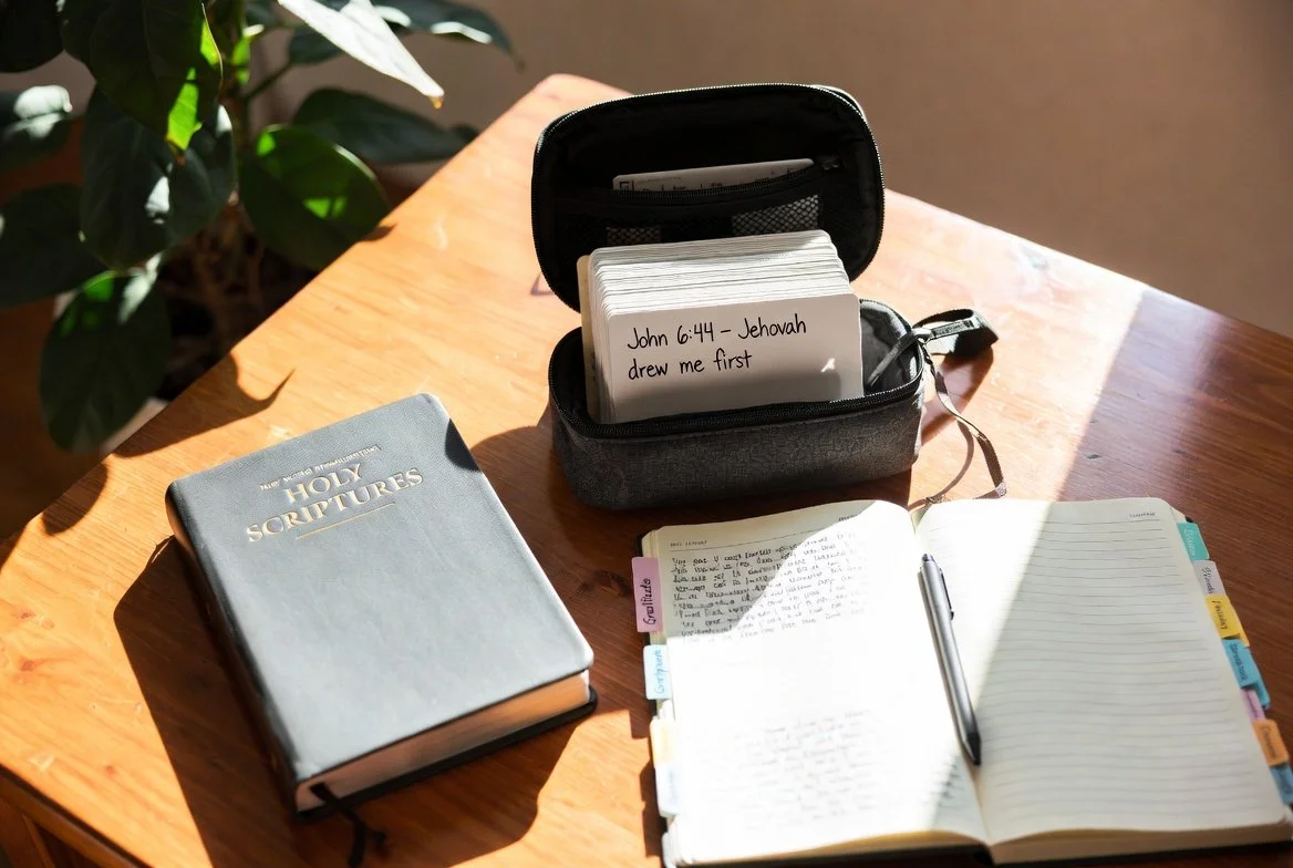 Hands gently holding an open emotional go-bag with New World Translation and encouraging notes, warm natural light