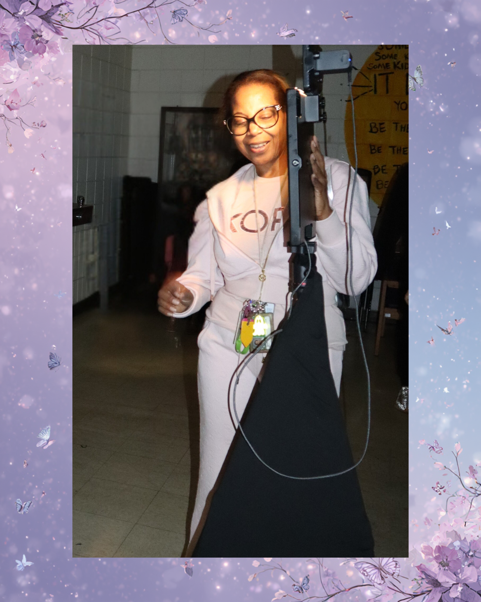 An elderly woman with glasses, smiling and dancing, standing behind a large piece of equipment in a room with dim lighting and decor.