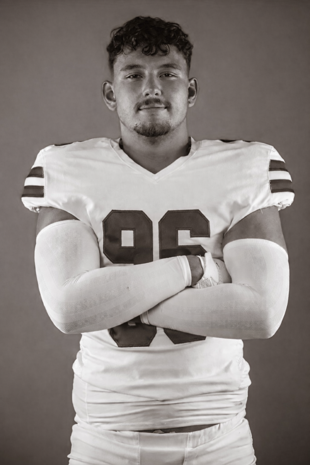 Black and white photo of a football player wearing a jersey with the number 96, arms crossed, looking at the camera.