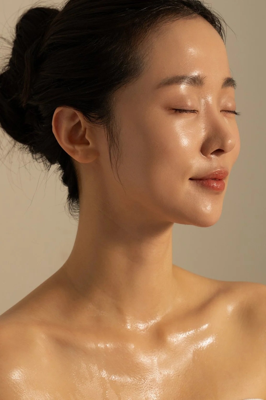 A woman with smooth, shiny skin, closed eyes, and a serene expression.