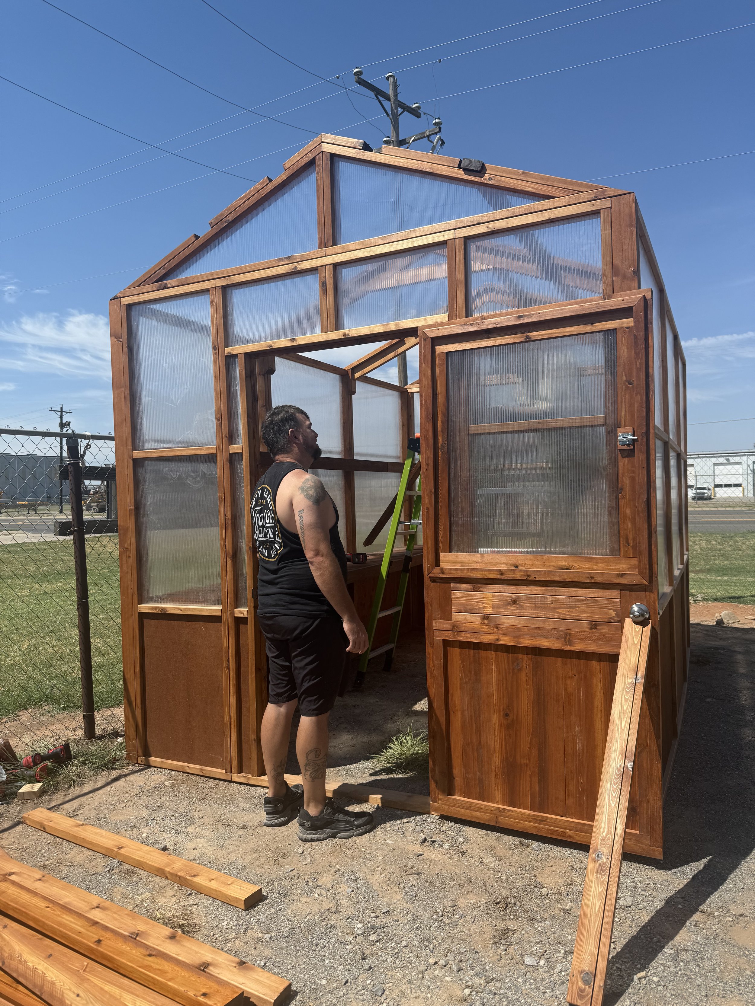 Woman at the door of a cedar greenhouse under construction