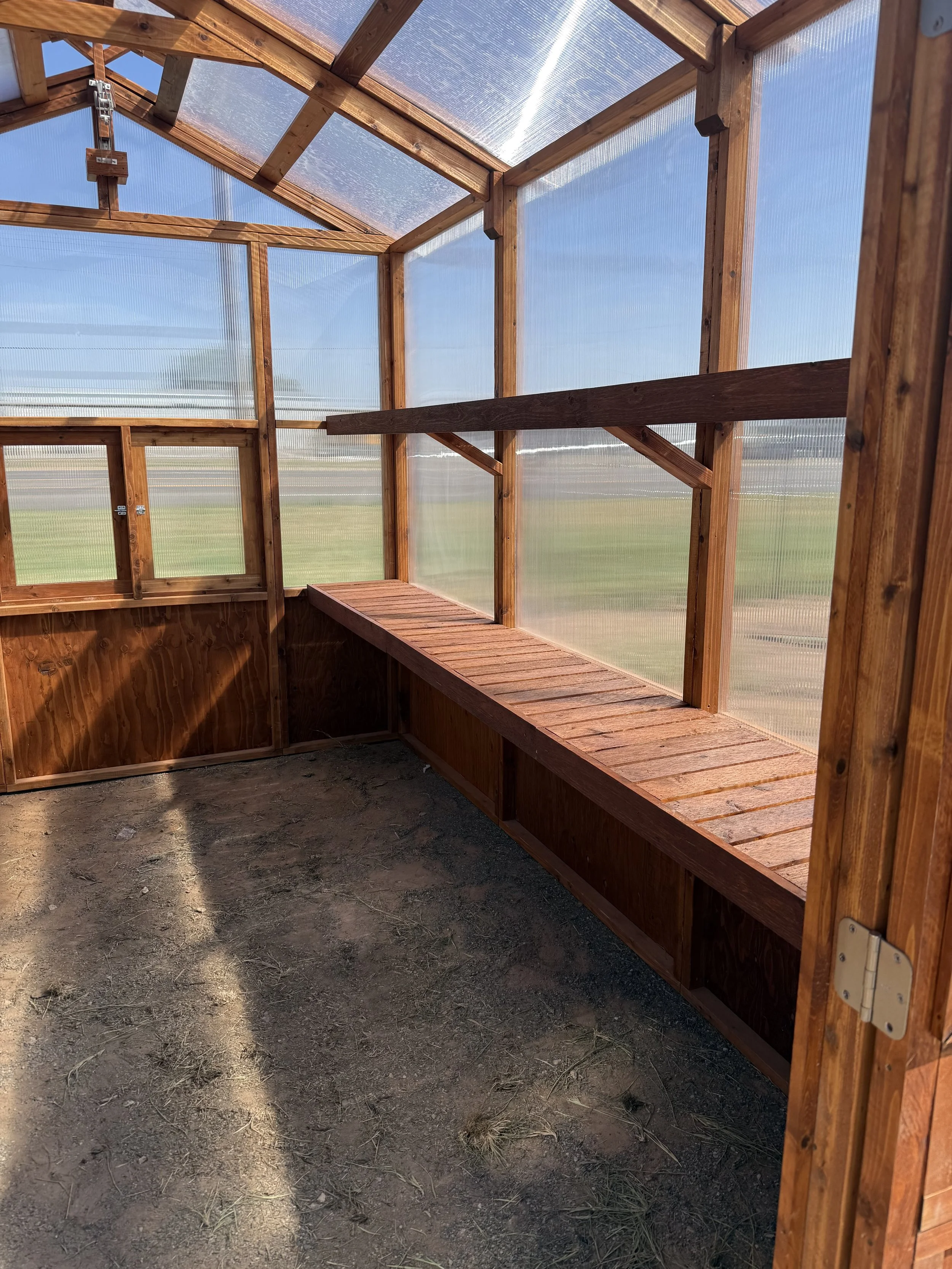 Interior of cedar greenhouse with wooden bench shelving