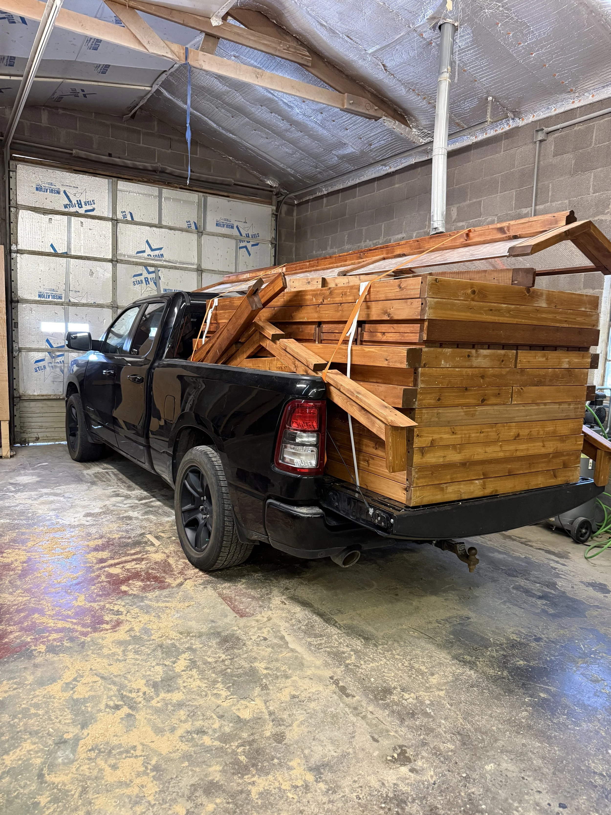 Black pickup truck loaded with cedar lumber inside a workshop