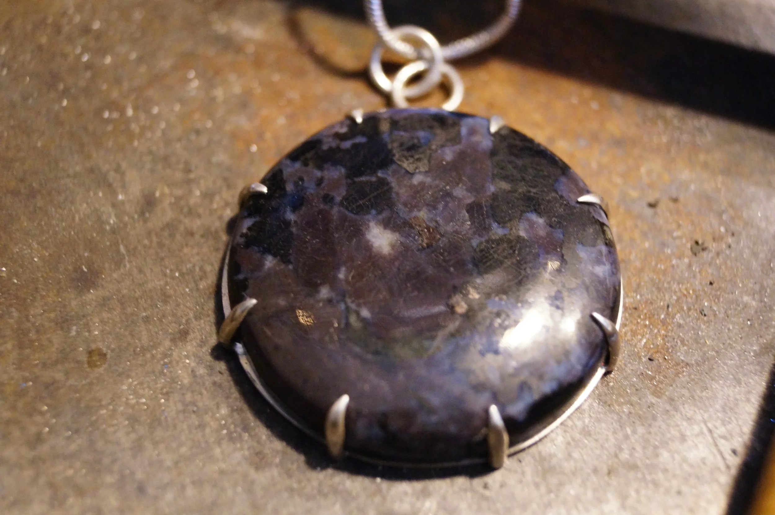 Round of Merlinite or Indigo Gabbro in a Sterling Claw Setting