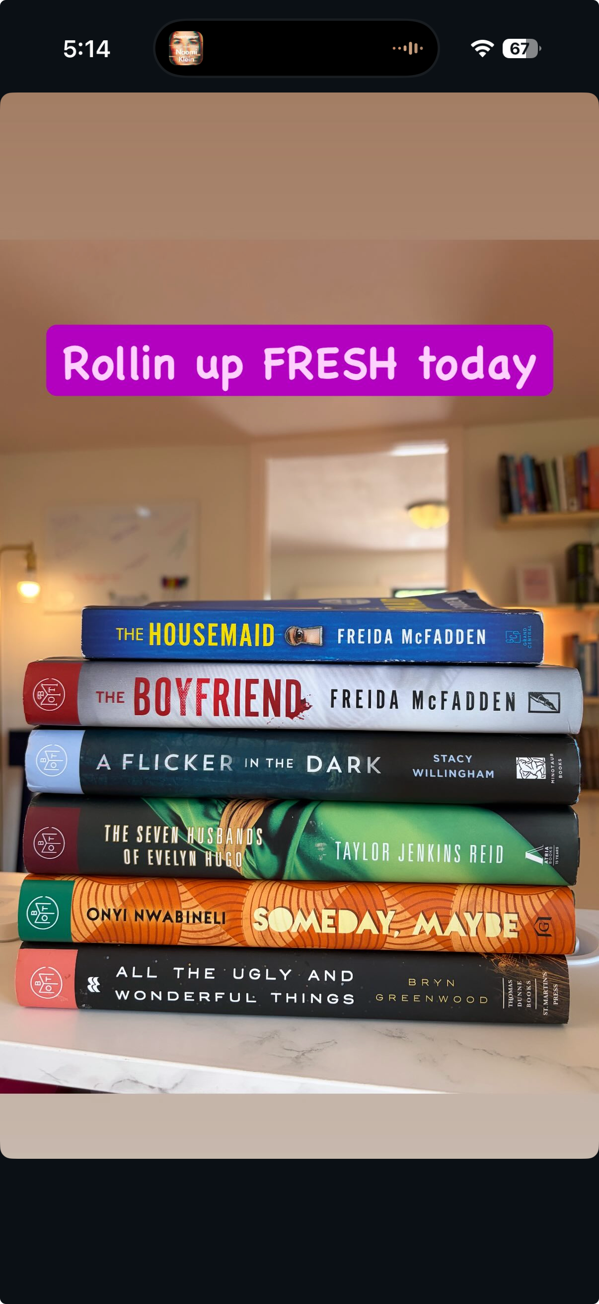 Stack of seven books on a white surface in a room, with a blurred background. The books are titled 'The Housemaid' by Freida McFadden, 'The Boyfriend' by Freida McFadden, 'A Flicker in the Dark' by Stacy Willingham, 'The Seven Husbands of Evelyn Hugo' by Taylor Jenkins Reid, 'Someday Maybe' by Onyi Nwabuneli, and 'All the Ugly and Wonderful Things' by Bryn Greenwood.