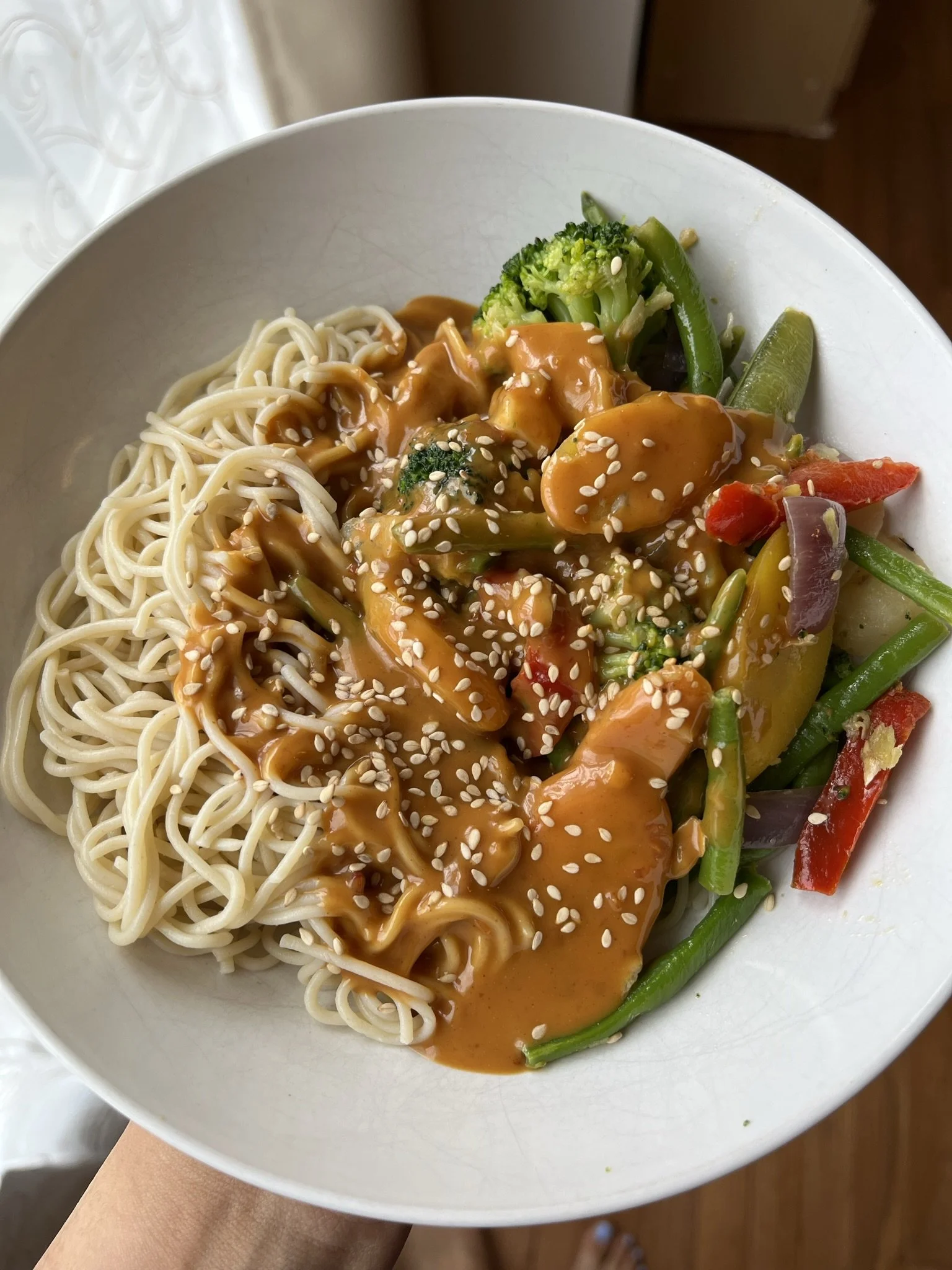 Bowl of Asian-style noodles topped with vegetable stir-fry and sesame seeds.