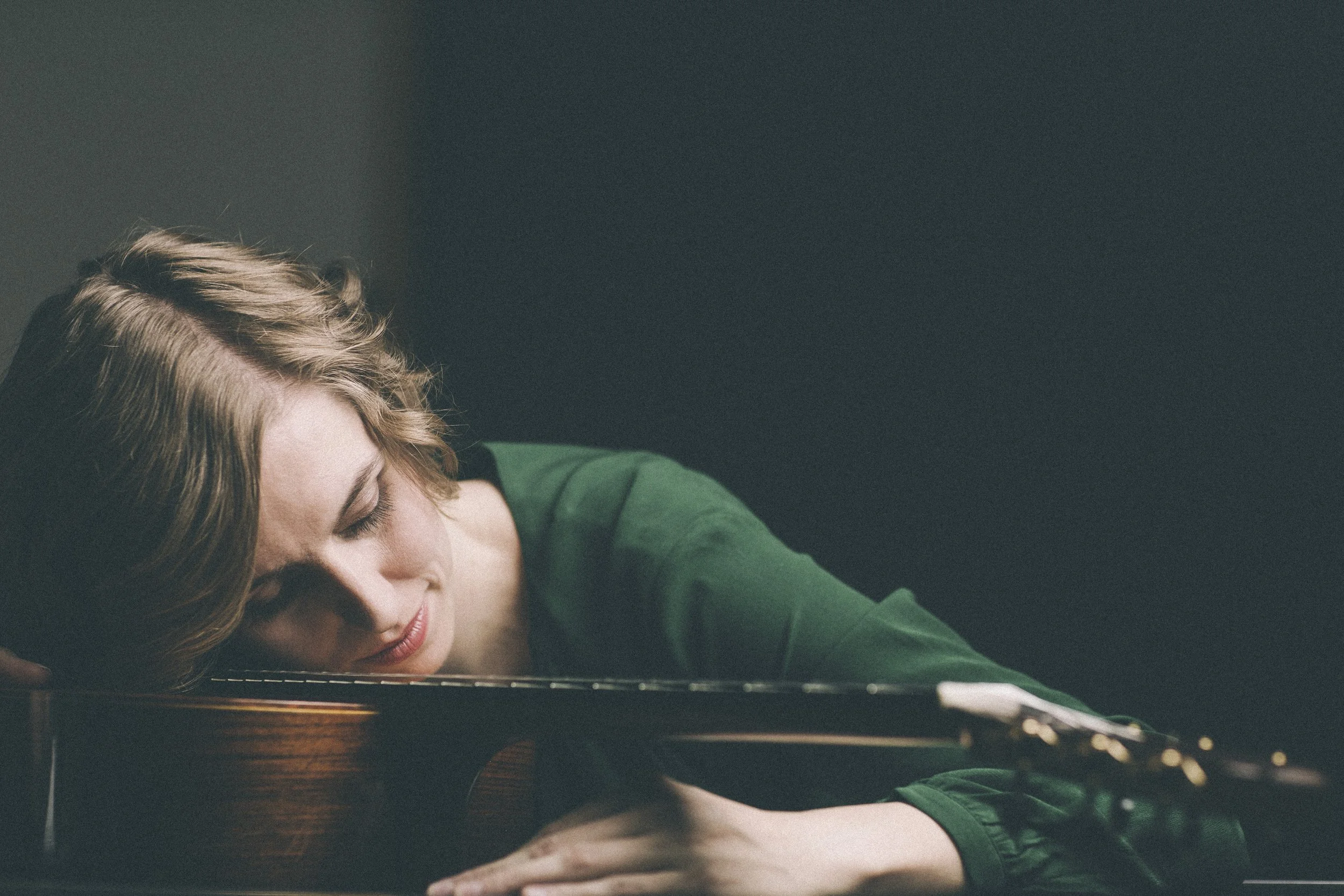 Eine Frau mit geschlossenen Augen lehnt auf einem Klavier und schläft.