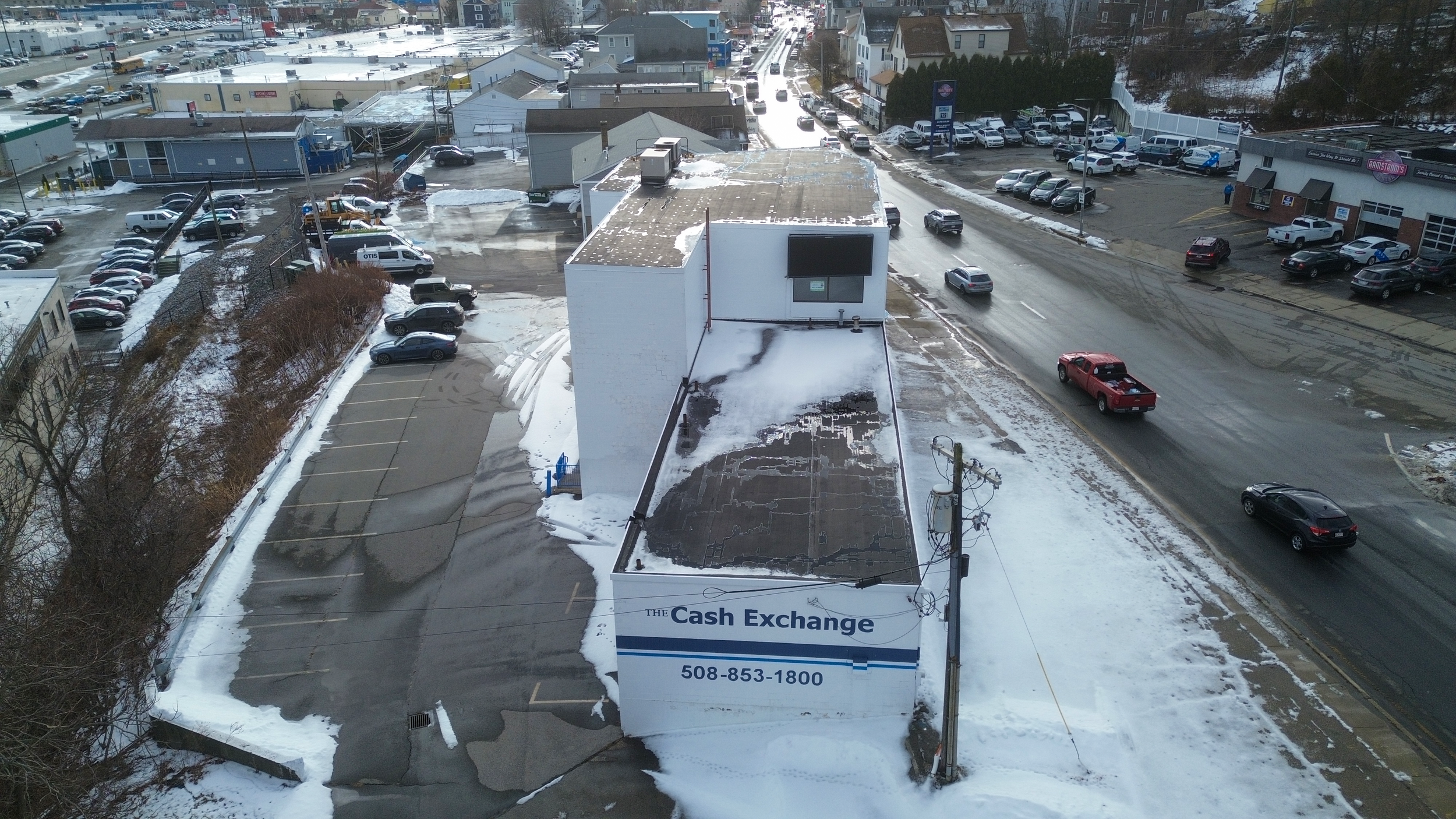 Aerial view of a building named 'The Cash Exchange' with a parking lot and streets in a snowy town.