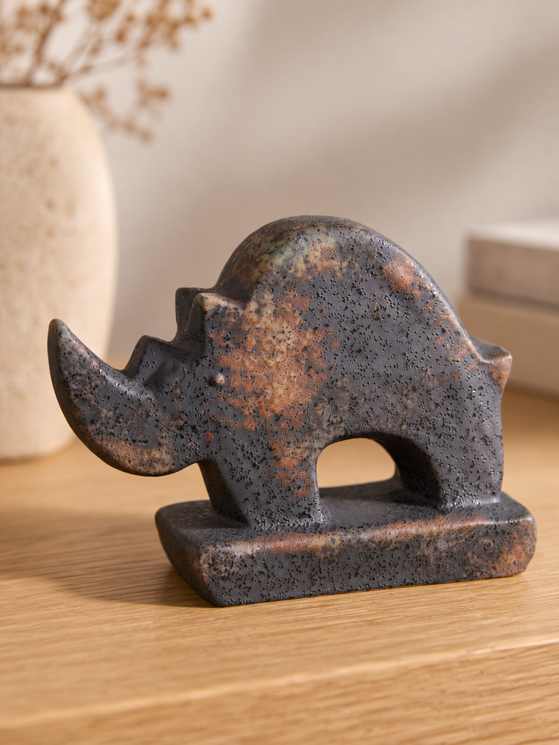 ceramic dark rhino sculpture on table.png