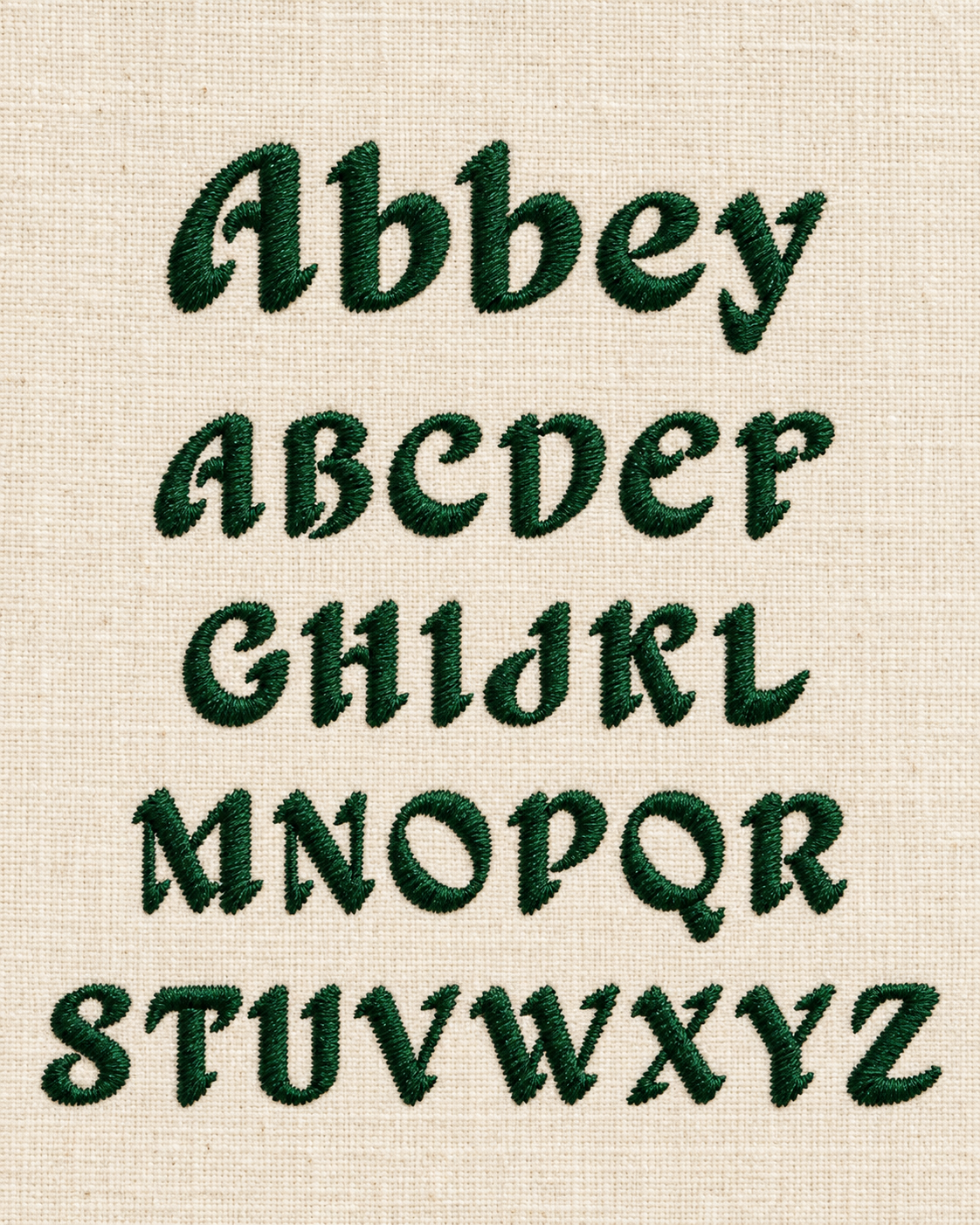 Embroidery of the lowercase alphabet letters in green thread on beige fabric.