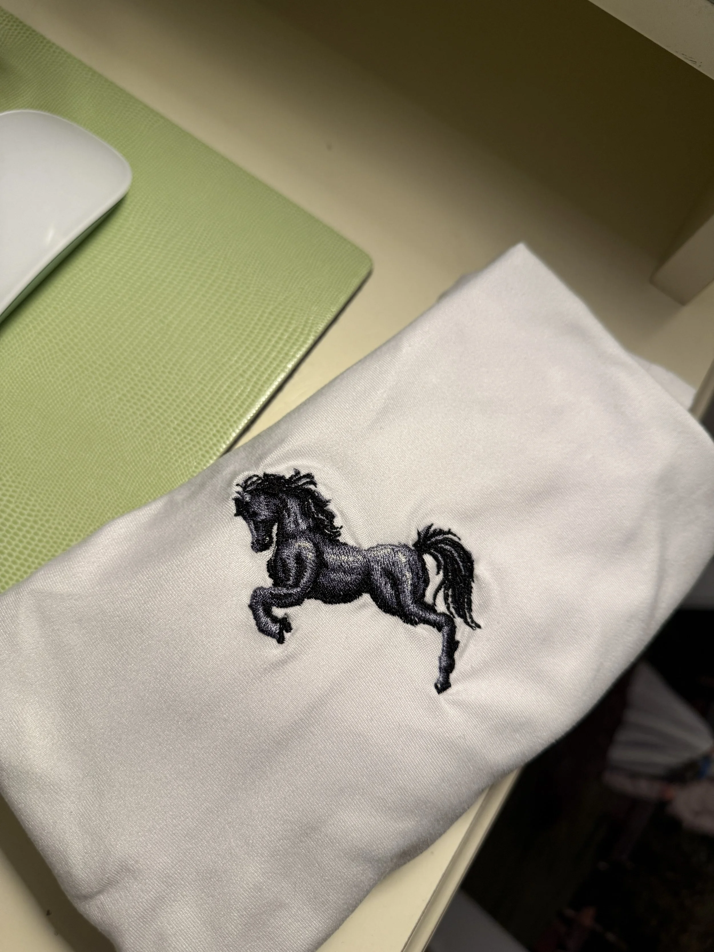 A white cloth with a black embroidered horse on it.