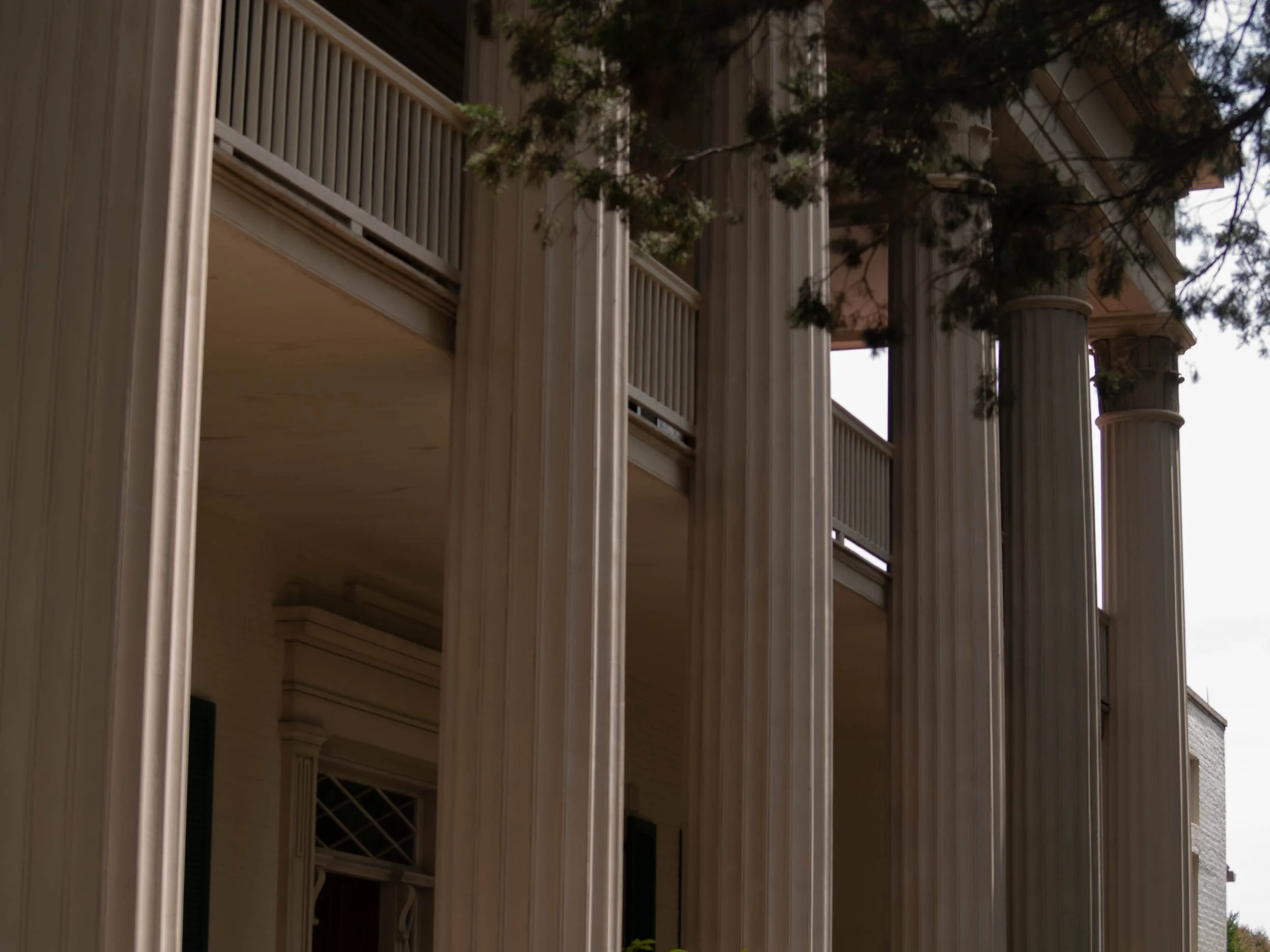 Close-up view of the columns and balcony of a classical-style building with white pillars and decorative molding.