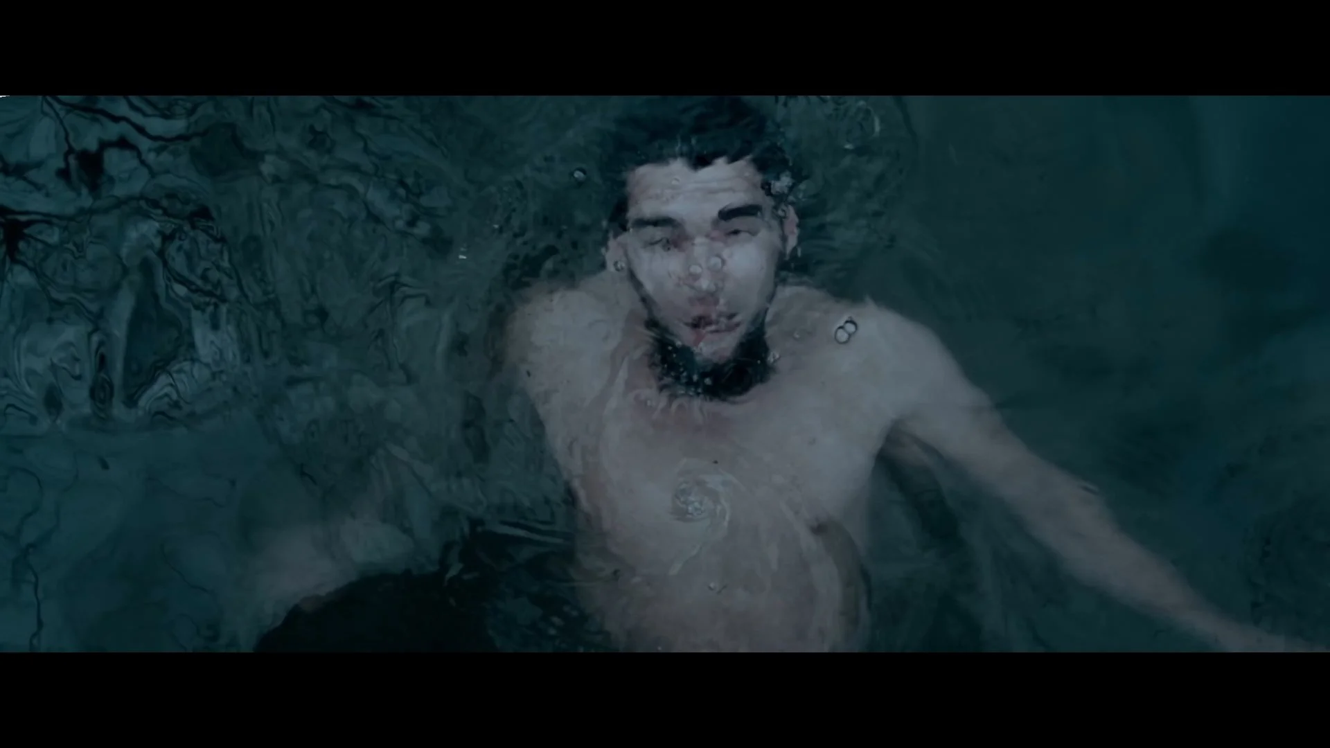 Mann schwimmt unter Wasser und schaut direkt in die Kamera.