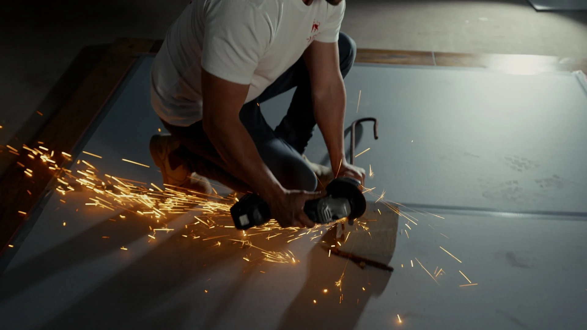 Worker cutting metal with an angle grinder, sparks flying during the cutting process.