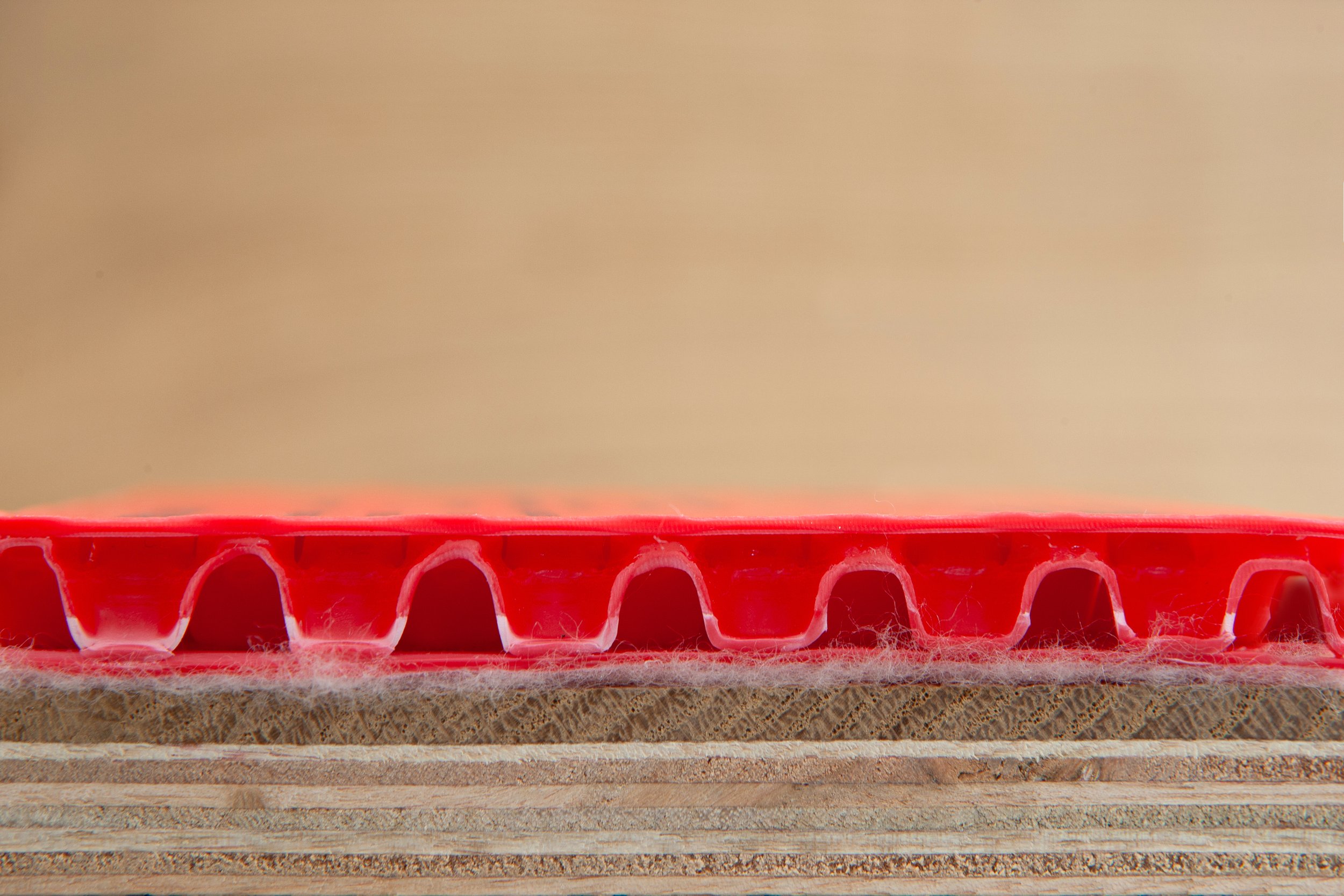 Close-up image of an orange plastic object with a circular hollow pattern, placed on a parchment-like surface.