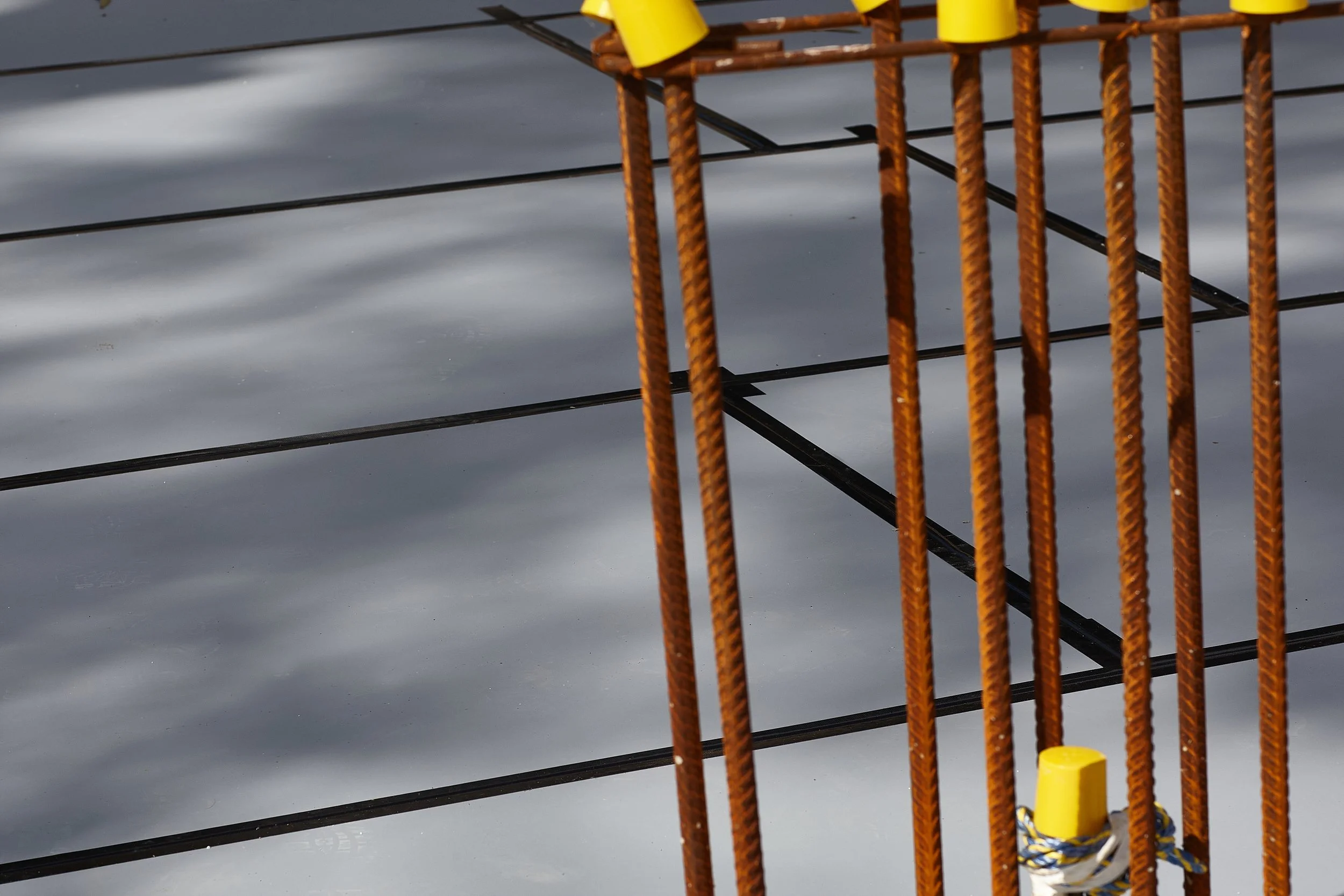 Close-up of a section of a fishing net against a water background, with yellow floats attached along the top edge.