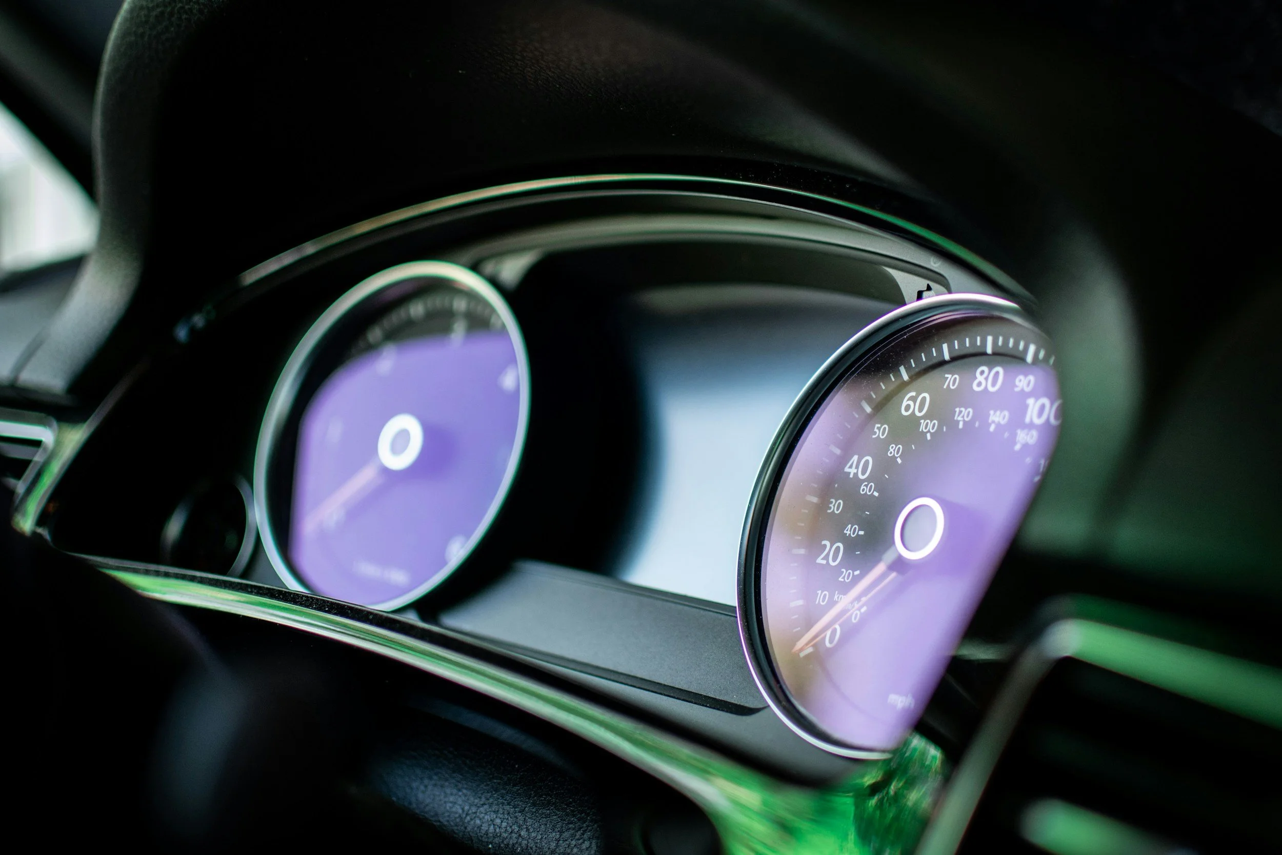 Close-up of a modern car dashboard with illuminated speedometer and tachometer gauges.