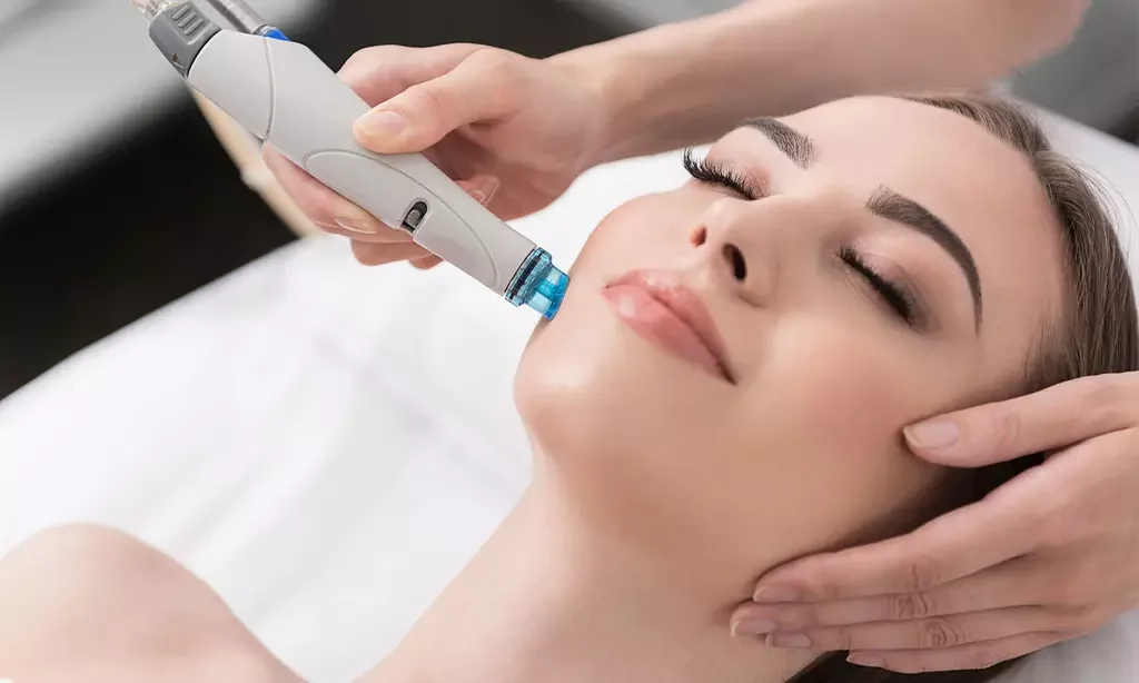 A woman receiving a facial treatment with a handheld device in a spa or clinic setting, lying with eyes closed, and a professional holding her face gently.