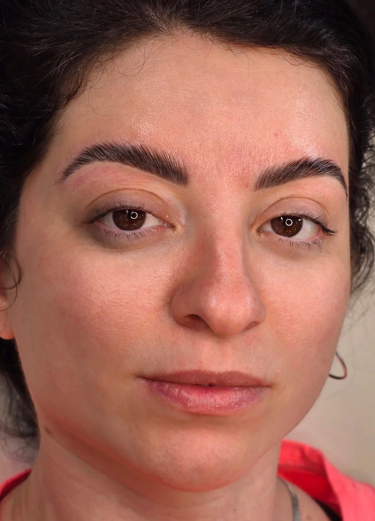 Close-up of a woman's face showing her makeup, including groomed eyebrows, and lightly applied eye makeup with natural lips.