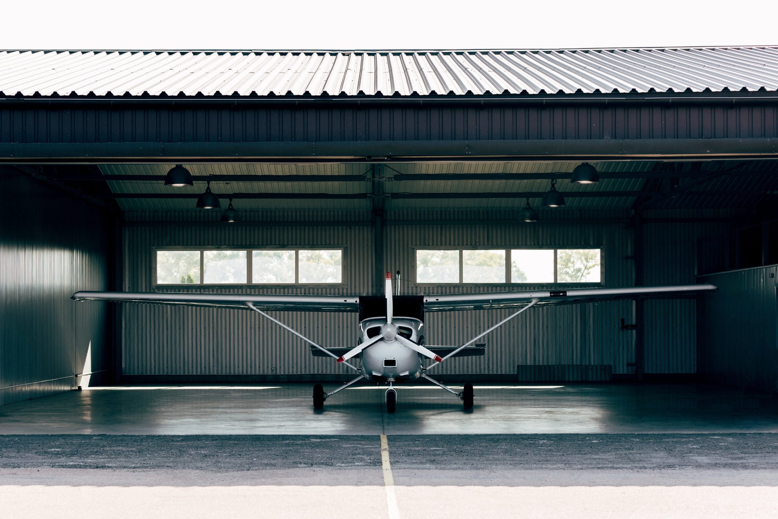 Small Cessna airplane inside a hangar with sunlight coming through windows.
