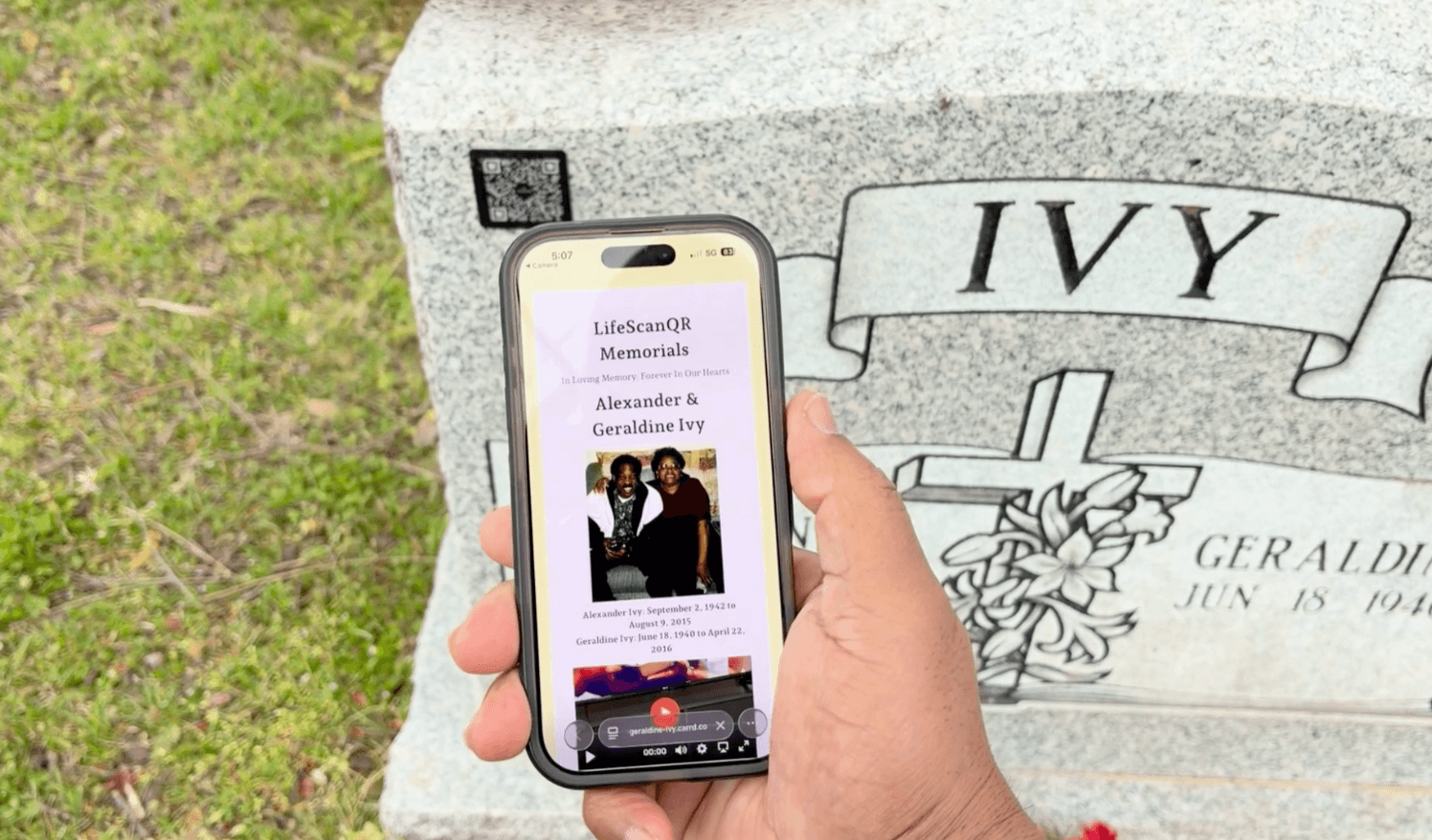 A hand holding a smartphone scanning a LifeScanQR code on a granite headstone to display a digital memorial profile