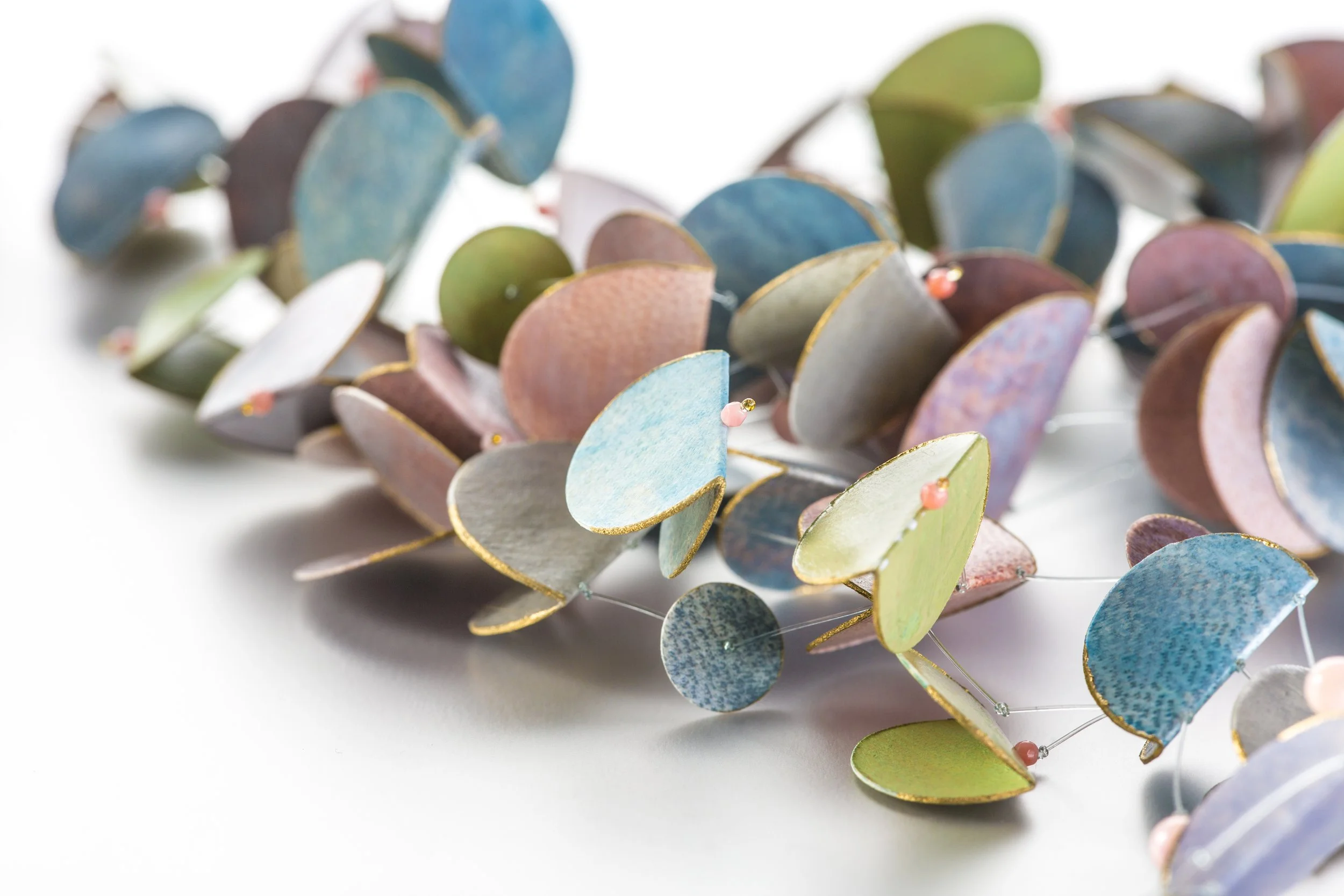 Kunstvoll gestaltete Pergamentkette aus bunten, schimmernden Elementen und Perlen.