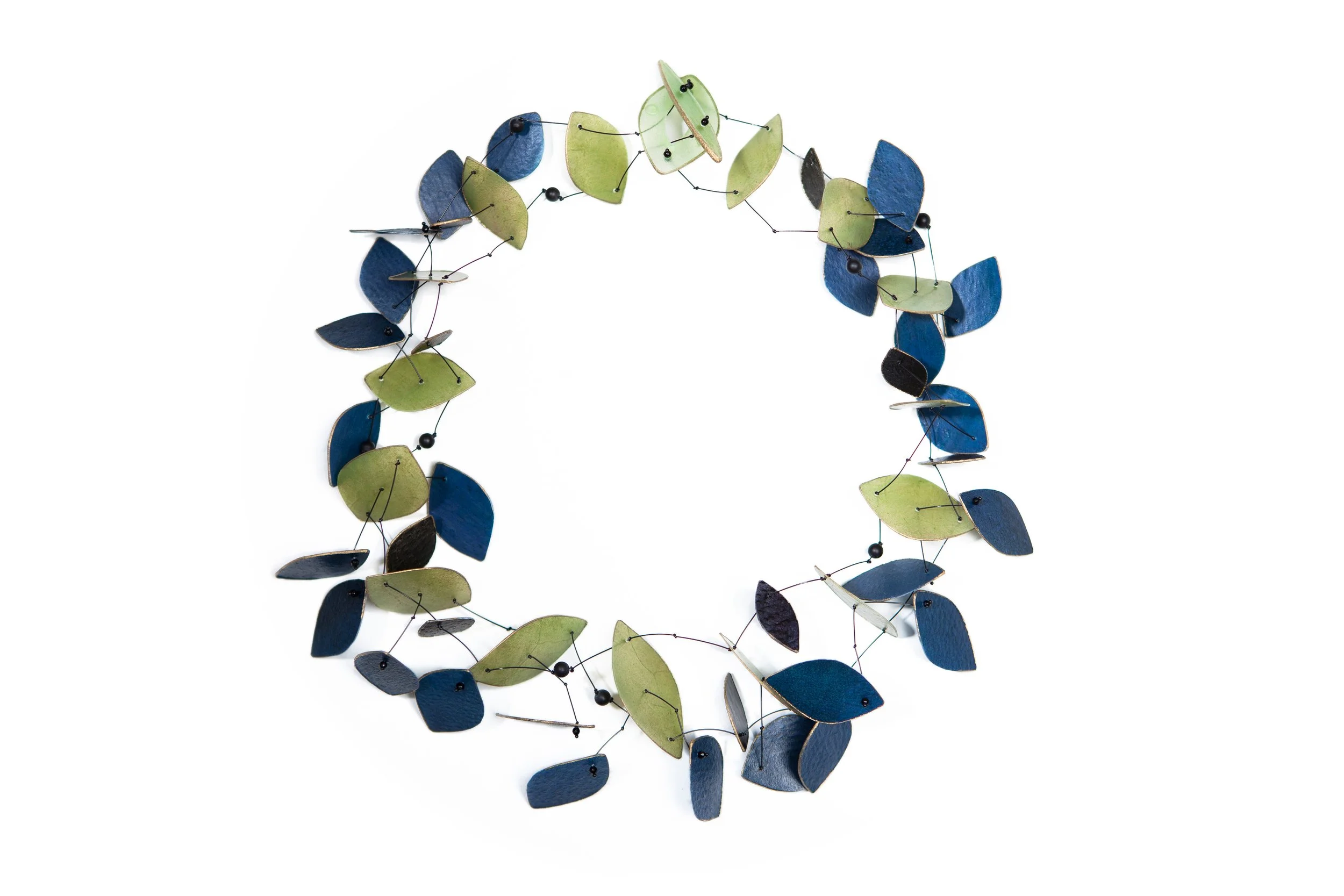 Pergamentkette aus blauen, grünen, schwarzen und weißen Elementen, verbunden durch dünne Drähte.