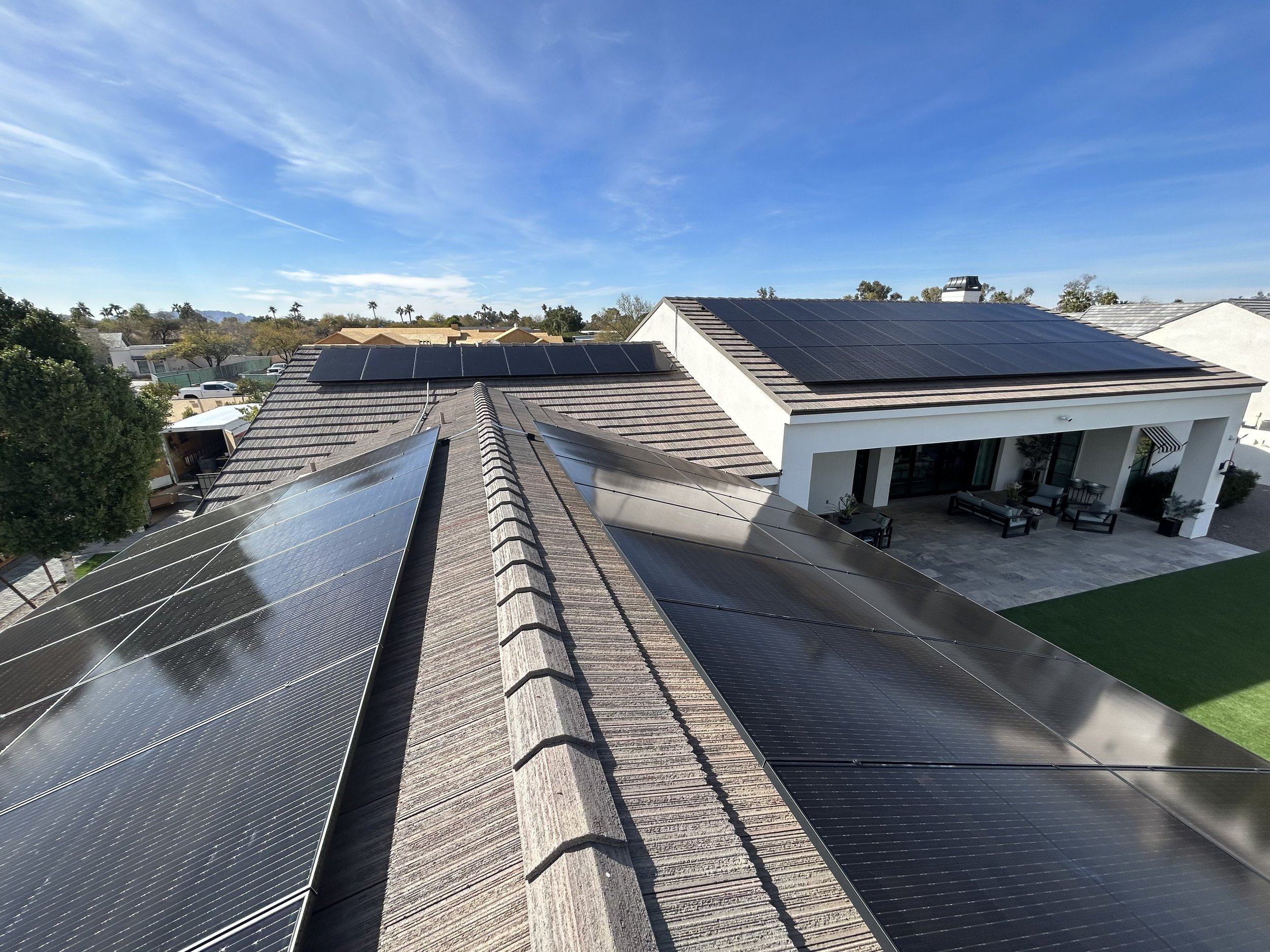 A house with solar panels on the roof, viewed from above on a clear day with blue sky.