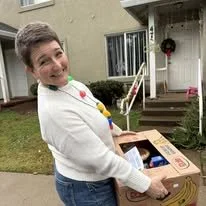 Child holding a cardboard box outside a house
