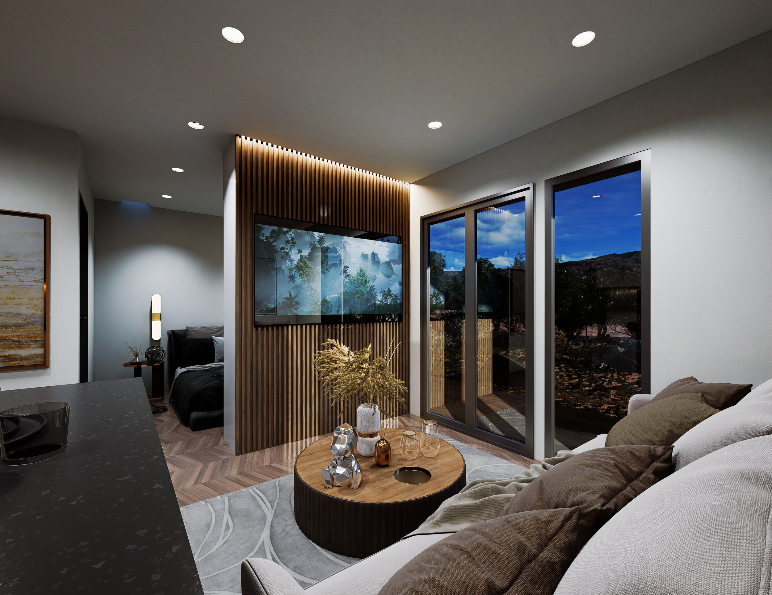 Modern living room with large glass sliding doors, a white sofa with brown pillows, a round wooden coffee table with decorative items, a wall-mounted TV on a wooden slat divider, and a view of trees and mountains outside at night.