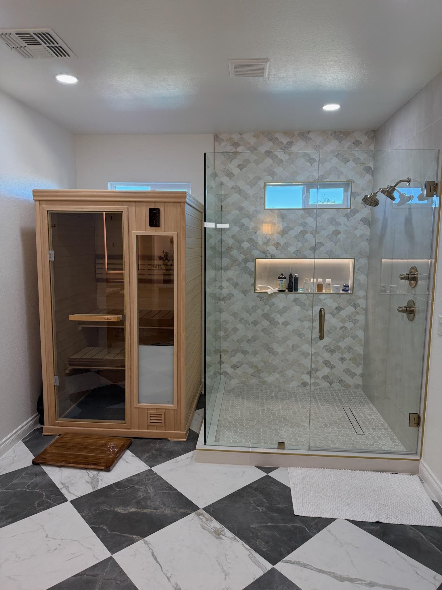 A bathroom with a glass shower enclosure and a wooden sauna.
