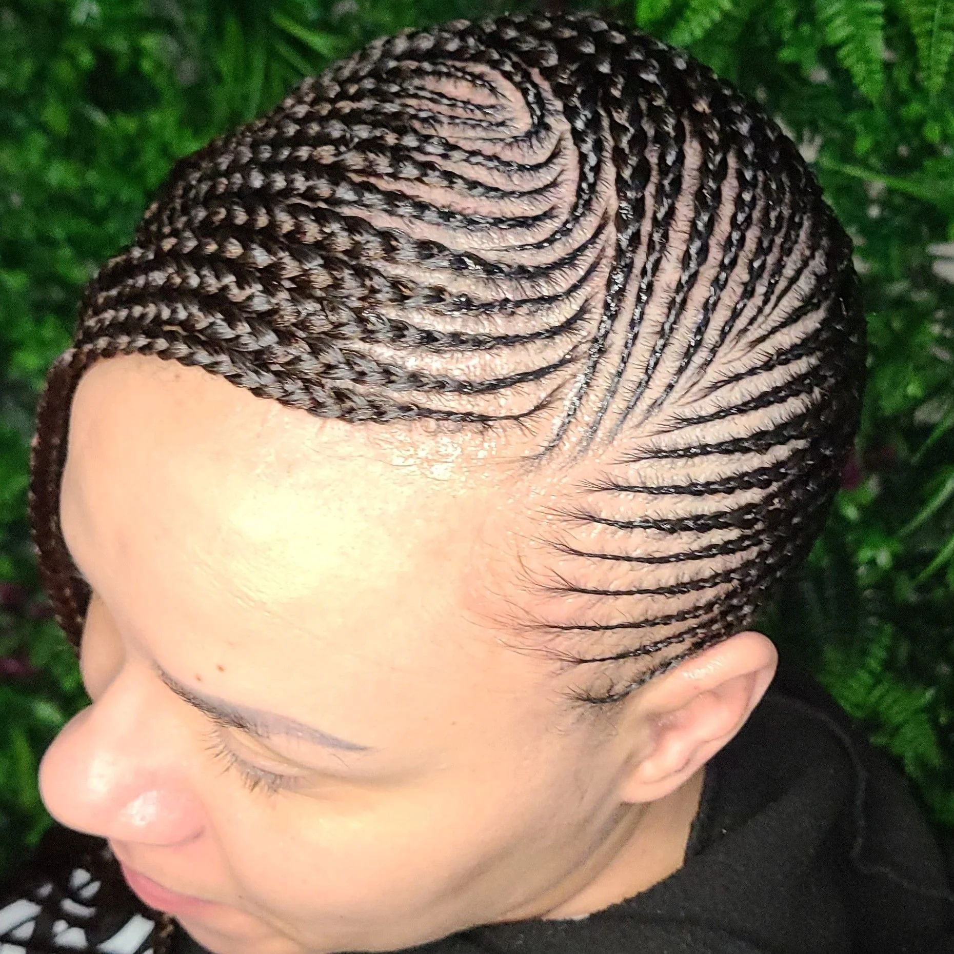 Close-up of a woman's head with intricate, neat braided hairstyle styled in a pattern covering the entire scalp.