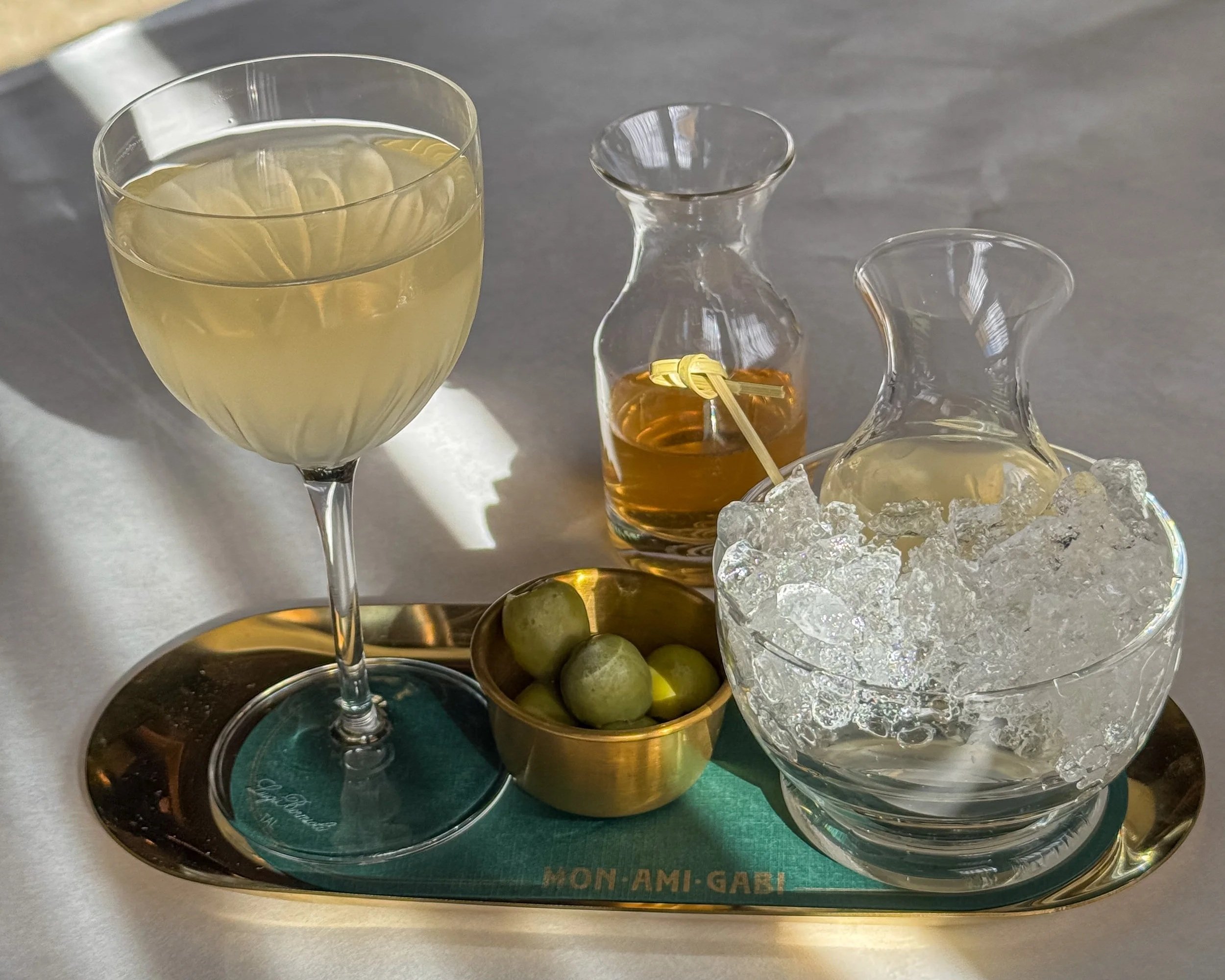 cocktail sitting on a brass tray on a table