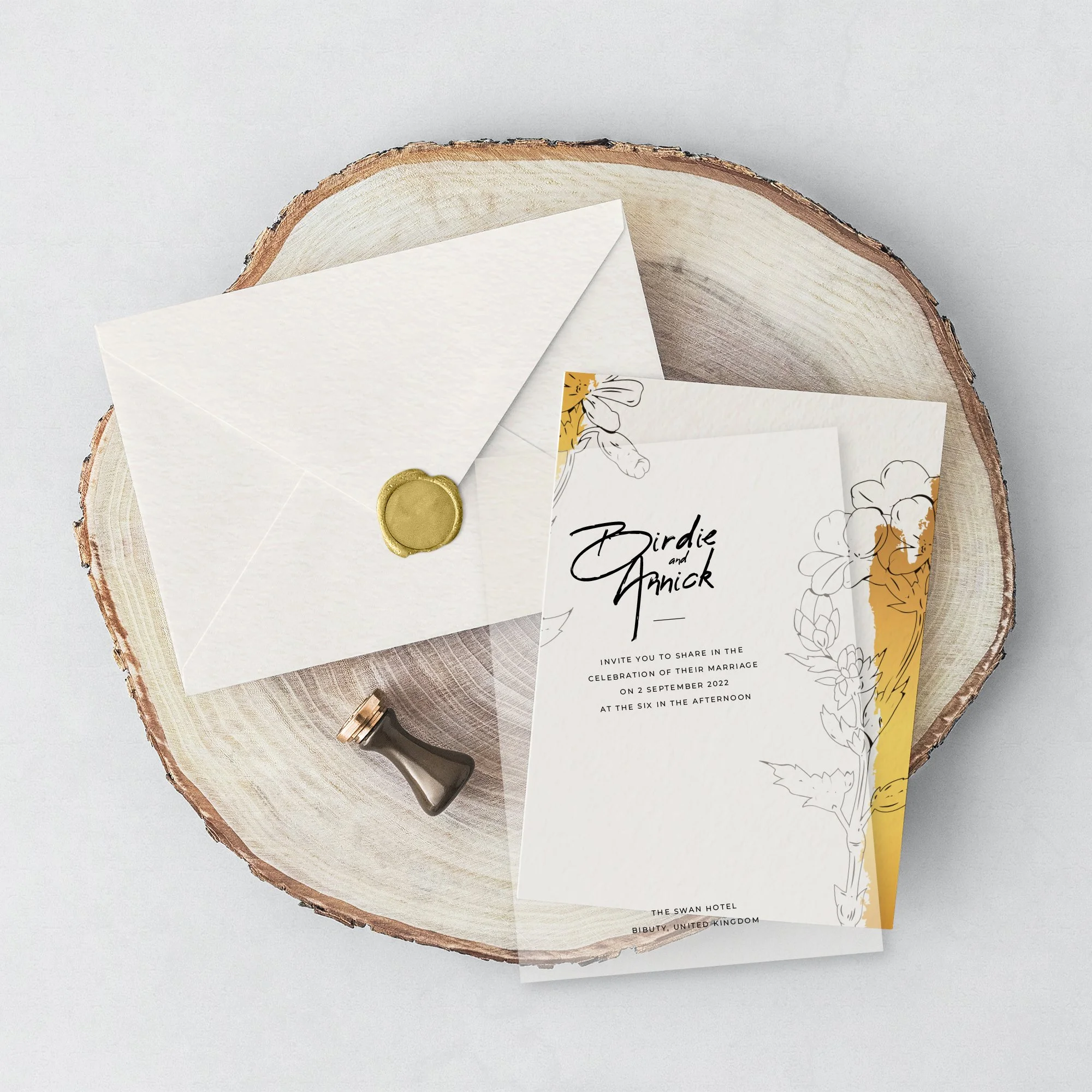 Invitation cards for a wedding or event, placed on a wooden slab with a white background, accompanied by a white envelope sealed with a gold wax stamp and a small black handled tool.