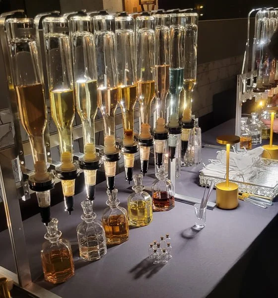 A bar setup with multiple bottles of alcohol, pouring mechanisms, and glasses, ready for serving drinks.