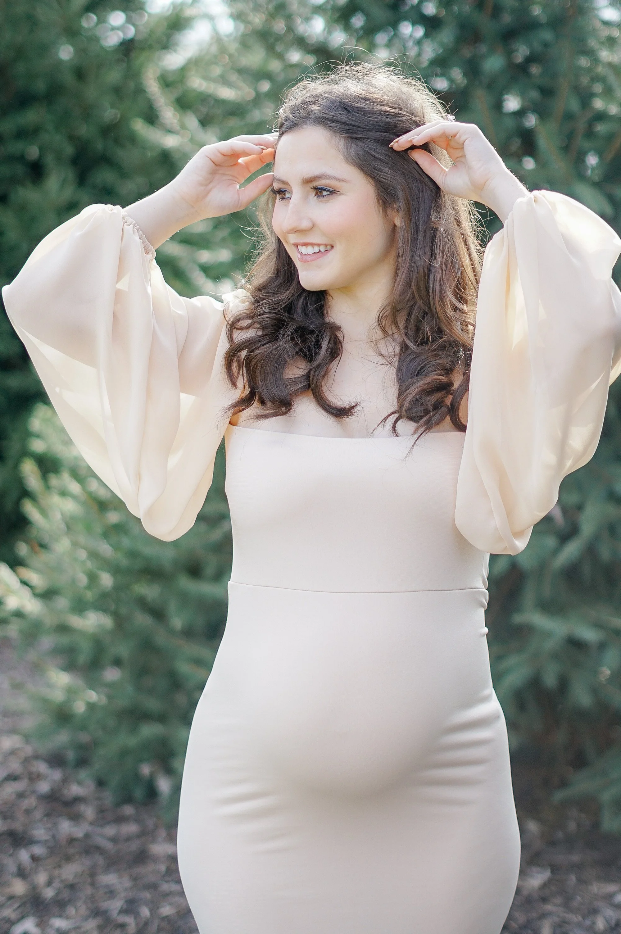 Expectant mother smiling during a sunny outdoor maternity session. 