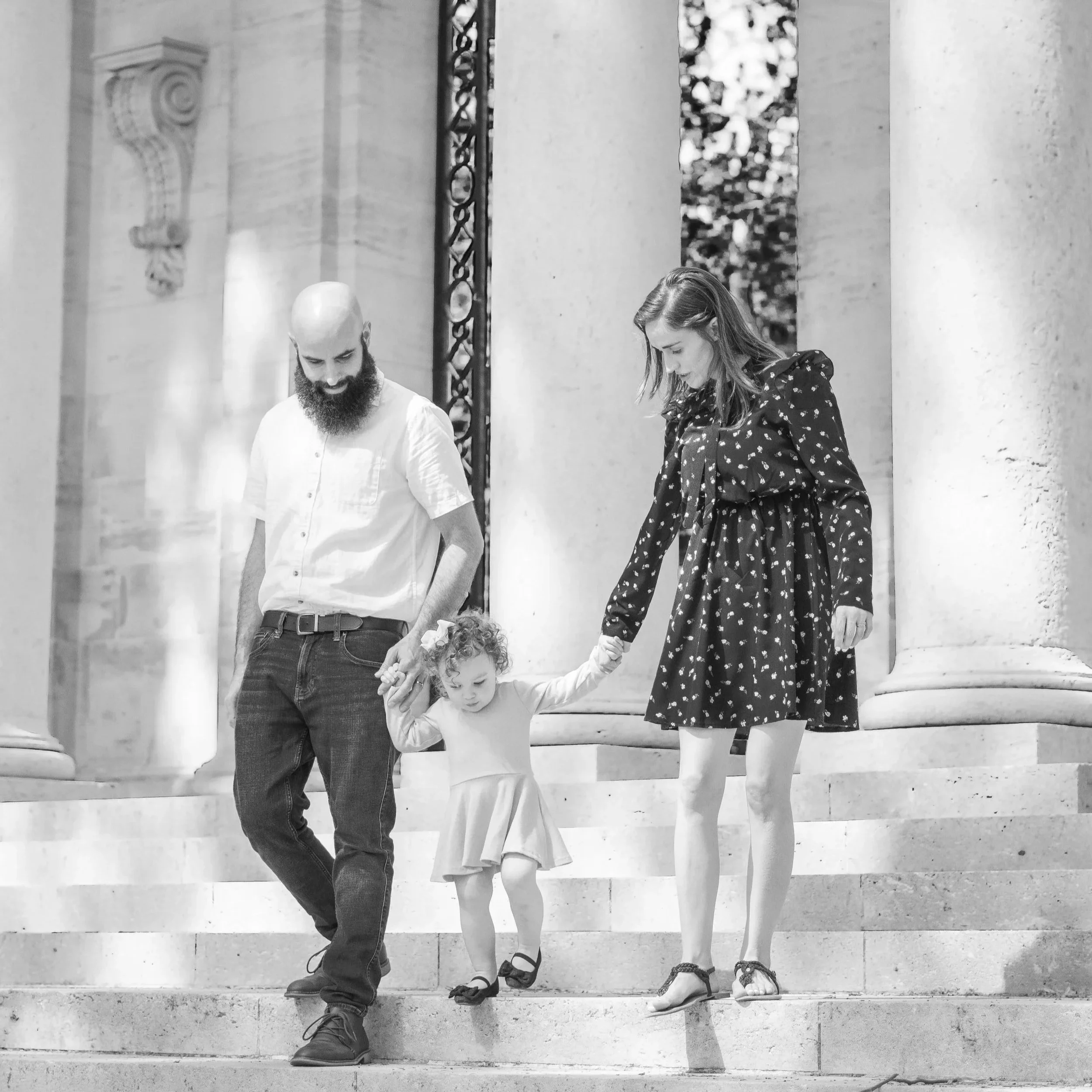 A family of three holding hands and walking down the step of the Rodin Museum in Philadelphia, for their family photo session.