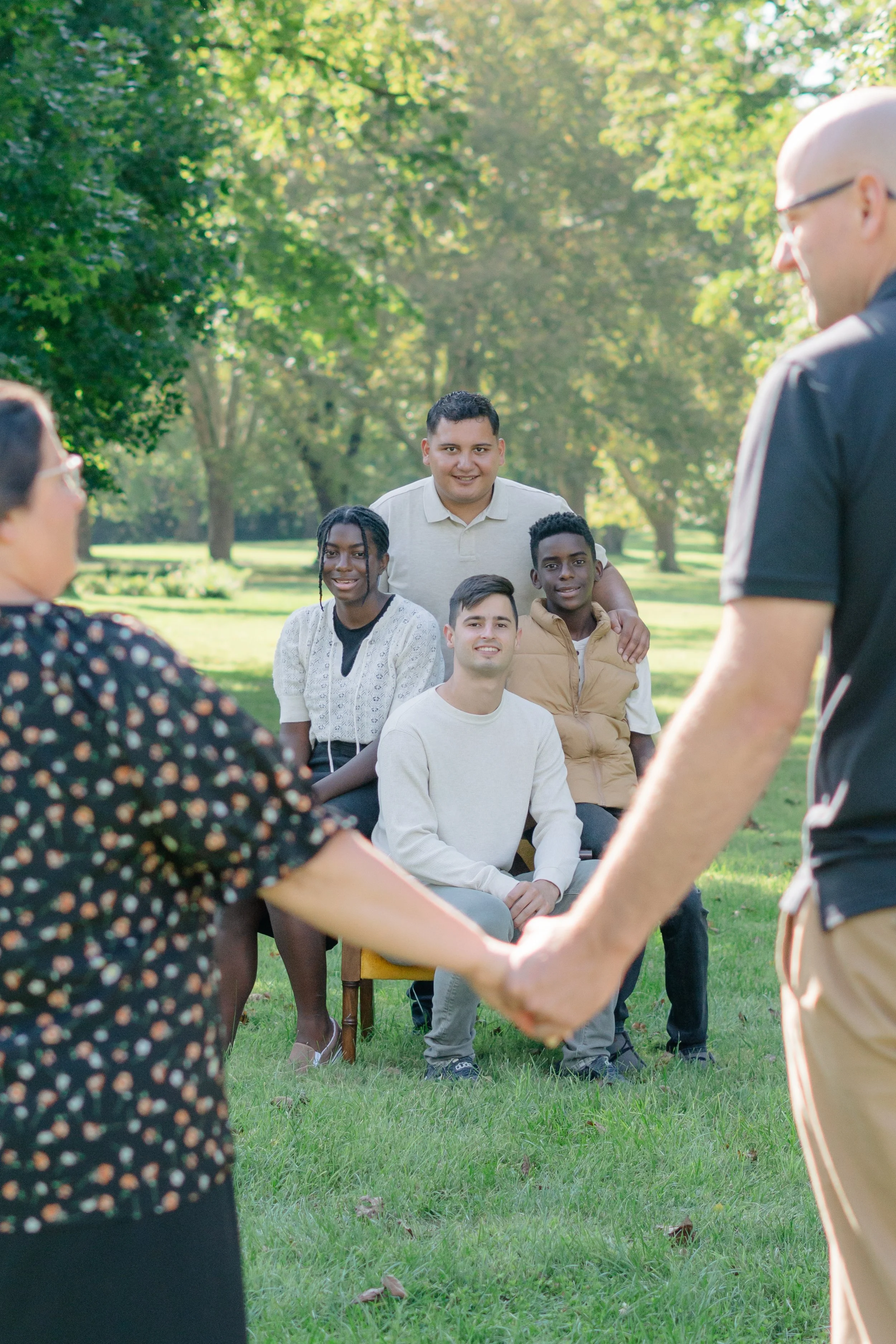 A family of teenagers at the park smiling for their family photo session.