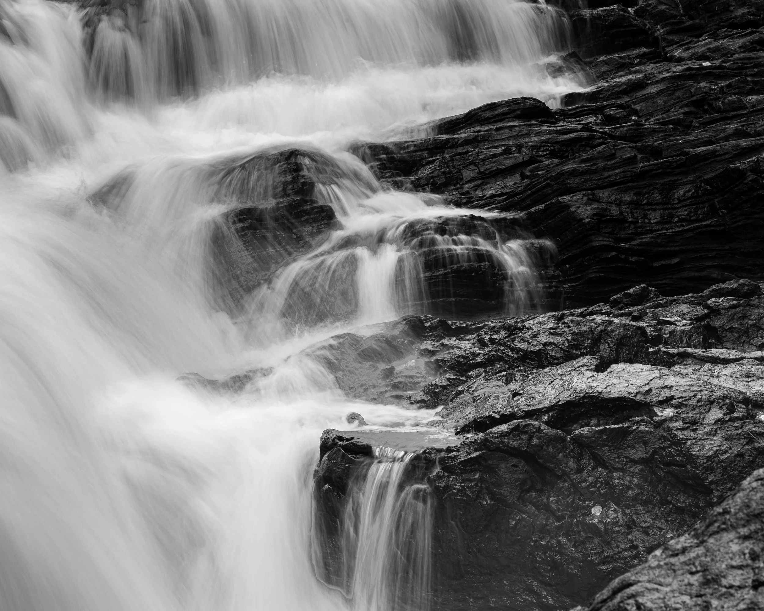 Black and white photo of a waterfall flowing over rocks.