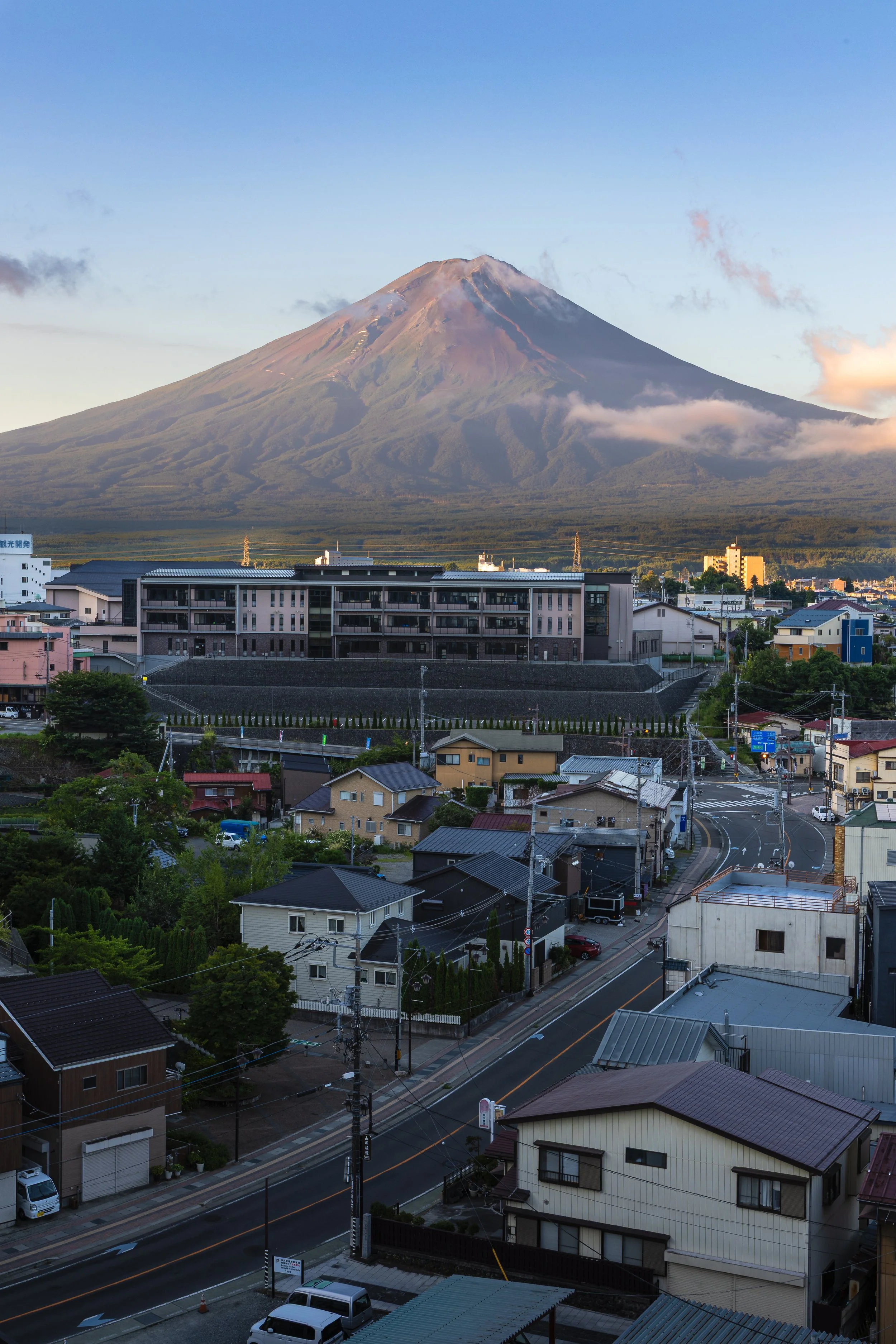 A view of a city with residential houses and streets in the foreground, with Mount Fuji in the background under a clear sky.